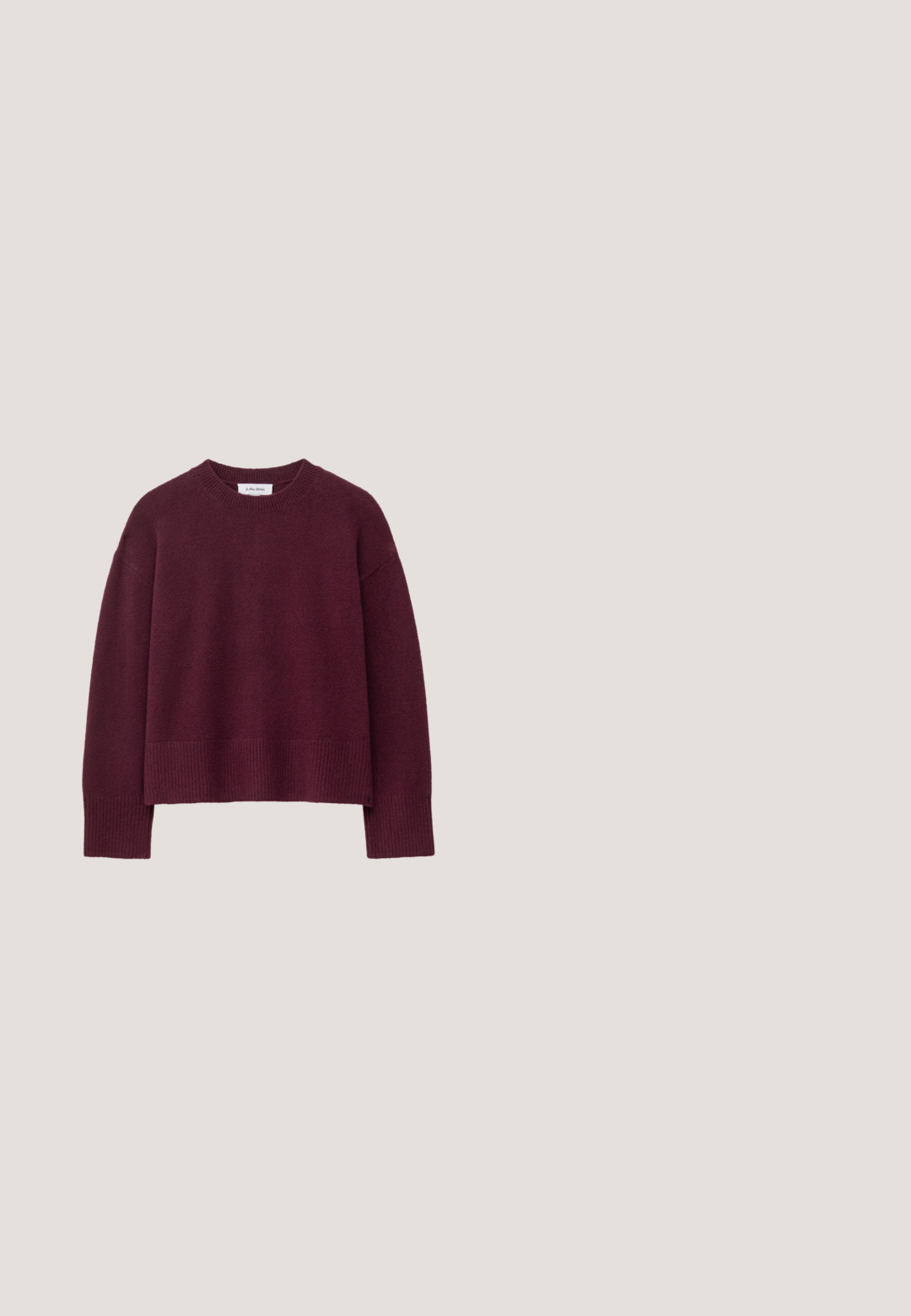 Burgunderfarbener Strickpullover mit einem gerippten Rundhalsausschnitt, oversized Schnitt und weiten Ärmeln, hergestellt aus einem weichen, strukturierten Stoff.; Dunkelbraunes, eng anliegendes Camisole mit verstellbaren dünnen Trägern und tiefem V-Ausschnitt.; Dunkelbraune, weit geschnittene Hosen mit dünnen vertikalen Nadelstreifen, Gürtelschlaufen und einem Frontreißverschluss.; Brauner spitzer Mule mit Absatz und Schnallendetail, der über einer glänzenden silbernen, gesteppte Lederoberfläche schwebt.; Dunkelbraune Wildlederhandtasche mit kurzem Riemen und abgerundeter rechteckiger Form auf einem einfarbigen hellen Hintergrund.; Hängende Ohrringe mit dunkelvioletten, runden, strukturierten ovalen, goldenen und unregelmäßigen dunkelbraunen steinähnlichen Perlen, vertikal gestapelt.