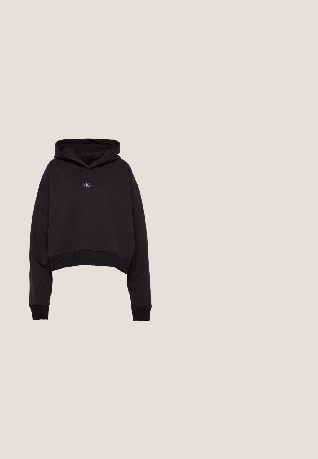 Zwarte cropped hoodie van zacht materiaal met een voorlogo-patch, geribbelde onderkant en manchetten, en een grote capuchon.; Zwart gebreid T-shirt met korte mouwen en witte raglanmouwen. Voorzien van de tekst "calvinklein" in het wit over de borst. Ronde halslijn. Zachte textuur.; Zwarte elastische broek met een uitlopende pasvorm, gekenmerkt door strakke lijnen en geen zichtbare versieringen. Gemaakt van een gladde, rekbare stof.; Zwarte lederen sneaker met dikke witte zool en CK-logo, zwevend boven patroon houten tegels buiten dichtbij groen en betonnen muur.; Zwarte gestructureerde leren handtas met een enkele schouderband en zilveren Calvin Klein-logo aan de voorkant, ritssluiting aan de zijkant.; Zilveren metalen hoepel oorbellen met een gestructureerd ontwerp, voorzien van een kleine post achter en branding op een van de hoepels. Ronde vorm met een gepolijste afwerking.