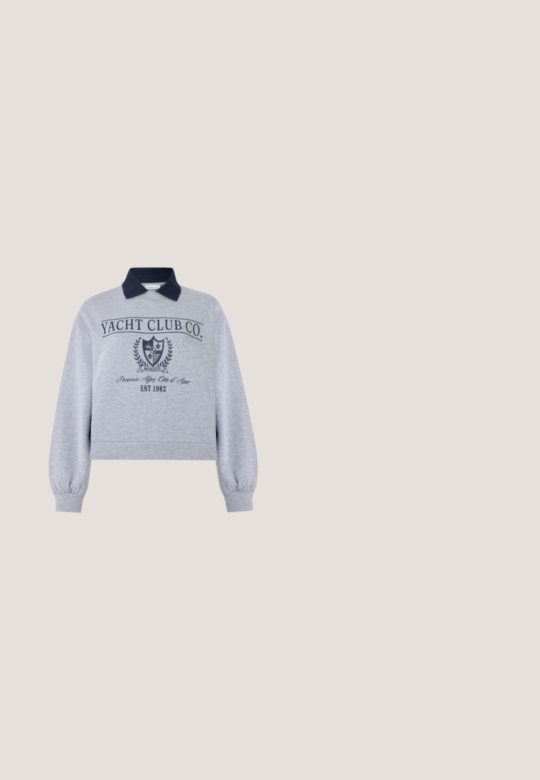 Sudadera de manga larga gris claro con cuello azul marino, texto "Yacht Club Co.", escudo de Mónaco y estampado "Provence Alpes Côte d'Azur EST 1982".; Camiseta negra de manga corta con cuello redondo. Presenta un gráfico blanco de un sol y el texto "Agradecido por cada pequeña cosa". Tejido suave.; Minifalda de mezclilla gris oscuro con corte recto, cintura elástica y detalles de costura sutiles sobre fondo liso.; Zapatilla gris y gris claro con una parte superior texturizada, lengüeta acolchada y detalles en negro. Cuenta con una gruesa mediasuela de espuma blanca y suela negra.; Bolso tote de pana gris con asas largas y un bolsillo frontal de parche, sobre un fondo blanco liso.; Par de pendientes de aro plateados brillantes de tamaño mediano con cierres metálicos finos sobre un fondo neutro claro.