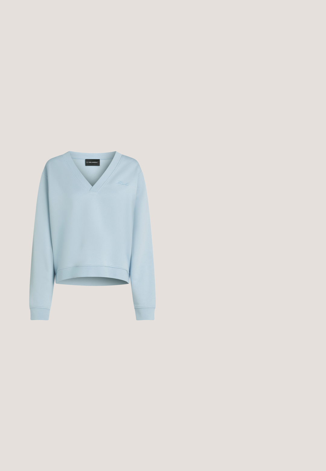 Lyseblå cropped sweatshirt lavet af blødt stof med V-udskæring, lange ærmer og et subtilt broderet logo foran.; Lysblå denimskjorte med knaplukning foran, krave, to store brystlommer og en buet kant. Materialet har en tekstureret overflade.; Bredde ben blå jeans lavet af denim, med en tekstureret overflade, fem lommer, lynlås og et klassisk taljebånd med en metalknap.; Denim sneakers med en tyk hvid platformsål. Har slidte kanter og metalliske detaljer, herunder et dekorativt logo på siden.; Mørkeblå denim skuldertaske med knyttede stropender og en enkel rektangulær form mod en hvid baggrund.; Sølv hoops øreringe med en poleret overflade og DKNY branding, præsenteret mod en simpel hvid baggrund.