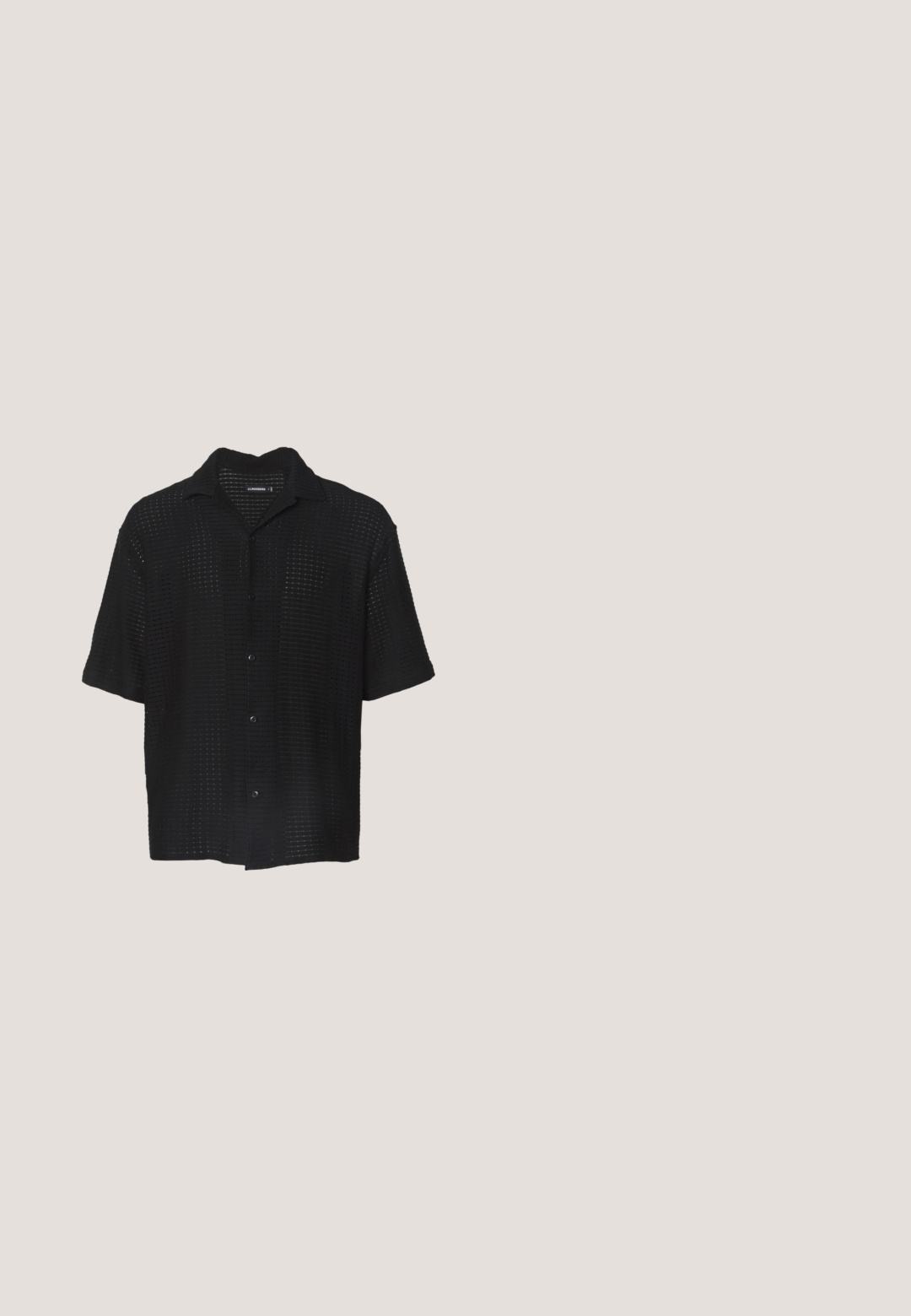Chemise noire à manches courtes avec un design en tricot ouvert texturé, dotée d'un col et d'une fermeture par bouton. Tissu léger avec une coupe décontractée.; Pantalons en lin noir avec une coupe droite, ornés de plis distinctifs à l'avant et d'une finition lisse et texturée.; Chaussure à enfiler en cuir lisse noir avec bout fendu arrondi et semelle plate beige, vue de côté sur fond blanc.; Lunettes de soleil à monture noire avec des verres rectangulaires teintés orange et des branches métalliques fines reposant sur une surface blanche.; Sac cabas en toile noire avec deux anses, poche avant et "LES DEUX" brodé en bleu sur la poche avant.; Ceinture en cuir tressé noir avec boucle argentée enroulée sur une surface blanche.