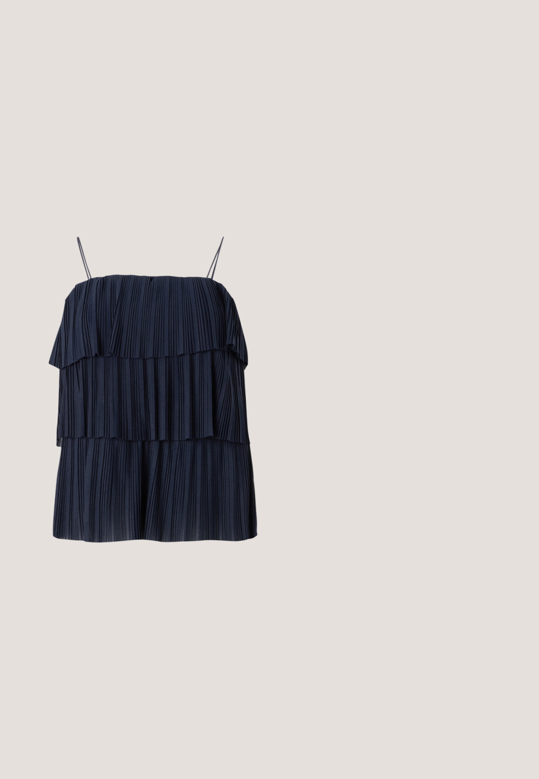 Haut plissé bleu marine avec un design en couches, des bretelles fines et une texture douce. Chaque couche présente des plis verticaux, créant de la profondeur et du mouvement.; Pantalons en denim à jambes larges de couleur bleu foncé, avec une taille haute, fermeture à bouton, poches avant et une texture lisse.; Mule noire en cuir à bout ouvert avec talon bloc, flottant au-dessus d'un sol moquetté gris avec un fond en verre flou.; Lunettes de soleil rectangulaires noires avec des verres bleus, dotées d'une monture épaisse et de la marque "vogue" en blanc sur les côtés. Fini brillant.; Petit sac à main noir brillant avec deux longues anses et des détails à cordon sur les côtés sur un fond clair uni.; Boucles d’oreilles créoles en forme d’étoile argentée avec une finition lisse et polie sur un fond blanc uni.