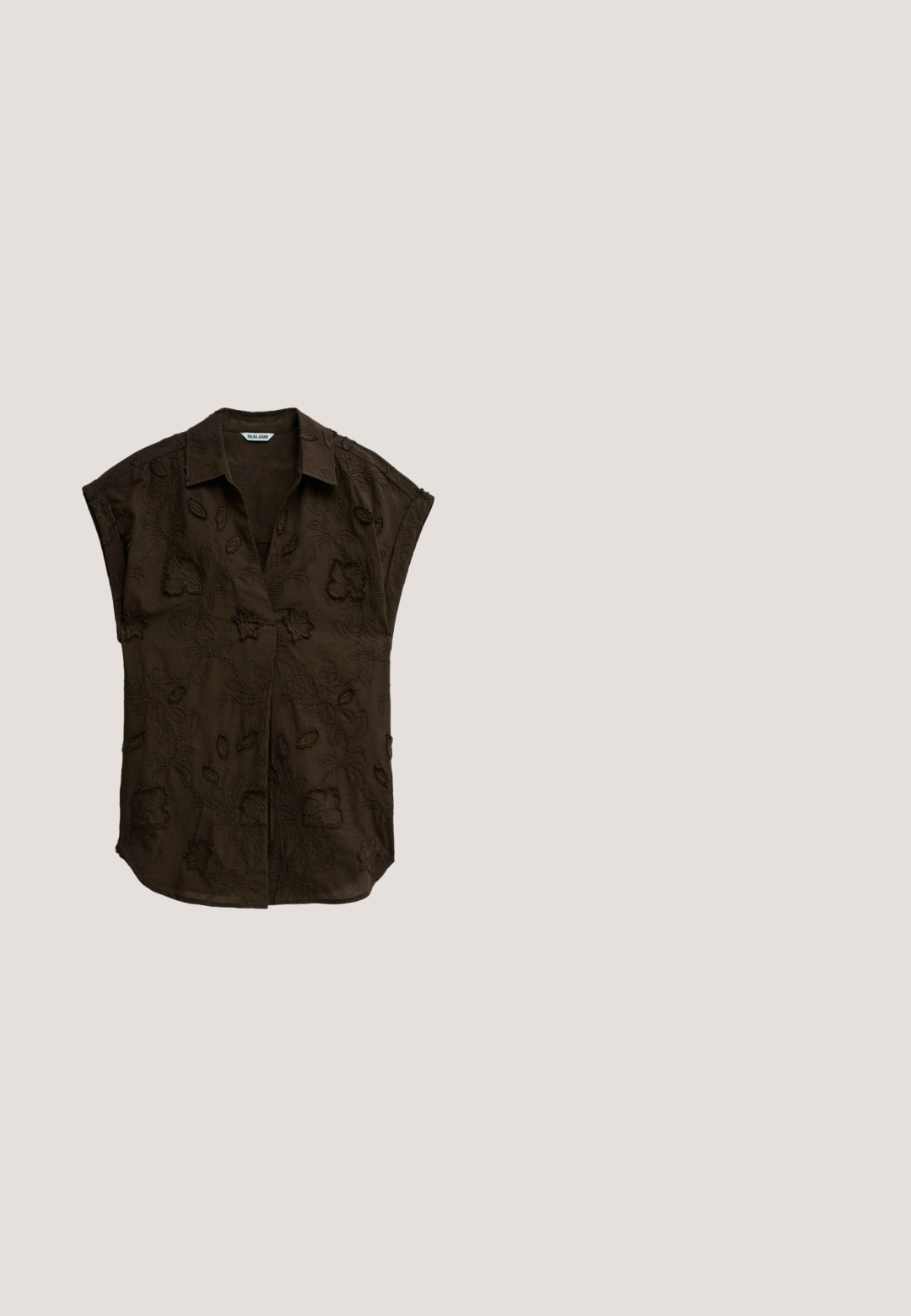 Blusa de manga corta marrón oscuro con patrones florales bordados, cuello y tapeta frontal oculta con botones.; Pantalones beige de cintura alta y pernera recta con costuras verticales, mostrados planos sobre un fondo blanco.; Tacón destalonado de punta puntiaguda tejido en color marrón con una hebilla decorativa grande y redonda, y un tacón delgado tipo kitten de altura media.; Gafas de sol estilo ojo de gato con montura carey, lentes tintadas en marrón y varillas delgadas, apoyadas sobre una superficie neutra.; Bolso de cuero marrón con una textura suave, presenta un borde superior curvado y una sola correa para el hombro. Diseño minimalista sin elementos metálicos visibles.; Anillo de oro con un centro circular que presenta acentos geométricos, pequeñas piedras incrustadas y una banda suave con grabados detallados.
