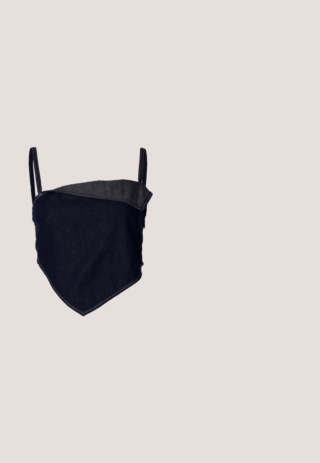 Bralette en denim avec un design ajusté. Tissu bleu foncé avec un panneau angulaire plus clair. Bretelles réglables et détails de couture visibles.; Jupe en denim gris à taille haute, avec cinq boutons en argent, des coutures verticales et un ourlet brut. A une silhouette ajustée et une texture douce.; Botte en cuir noir mi-mollet avec des clous argentés en motifs losanges, sangles à boucles près du haut et de la cheville, et un talon bas incliné.; Sac en tissu gris foncé avec une anse courbée, texture douce et forme arrondie. Pas de matériel ou d'embellissements visibles.; Paire de boucles d'oreilles créoles argentées brillantes avec fermoirs en fil fin, présentée sur un fond gris clair.; Ceinture en cuir noir avec une grande boucle en métal argenté dotée de détails complexes et d'accents décoratifs à chaque extrémité.