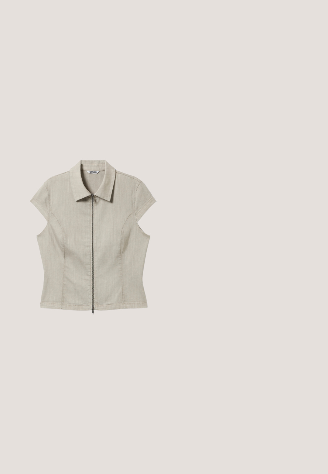 Beige shirt met korte mouwen, een kraag en een centrale ritssluiting, getailleerde naden en een label met de tekst "WEEKDAY" aan de binnenkant van de kraag.; Witte cargoshorts met een elastische tailleband en trekkoord, voorzien van twee zijzakken en verstelbare hemkoordjes. Gemaakt van lichtgewicht stof.; Olijfgroene suède Mary Jane-sneaker met zwarte rubberen zool, geribbelde neuskap, stervormige studs en twee gespen van messing.; Bruine plastic zonnebril met een langwerpige cat-eye vorm, donkere lenzen en zilveren stipaccenten aan de zijkanten.; Groene en beige reistas met voorvak met rits, beige logo, twee handvatten en verstelbare schouderband tegen een lichte achtergrond.; Cuffarmband vervaardigd uit gedraaid zilverkleurig metaal, met een gevlochten ontwerp, open uiteinden en een gladde textuur.