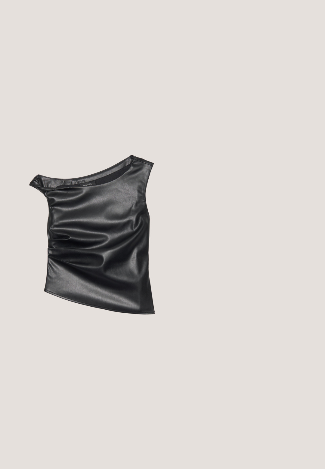 Haut noir asymétrique en faux cuir lisse. Présente un design drapé et un éclat subtil, avec un col rond et une texture superposée.; Jean noir taille haute à jambes larges en denim, avec une fermeture à bouton, des passants de ceinture et deux poches arrière avec des accents cousus.; Chaussure à bride arrière en cuir verni noir avec un petit talon bloc reposant sur un tapis bleu texturé à motifs ondulés et un mobilier gris rembourré.; Sac d'épaule en cuir marron clair en forme de croissant avec une sangle ajustable et une fermeture éclair supérieure sur un fond uni.; Boucles d'oreilles en argent avec une forme organique et abstraite. Surface lisse et brillante avec un design effilé. Présente des courbes subtiles et un détail central en ligne.; Ceinture en cuir noir avec boucle rectangulaire en argent, enroulée et posée sur une surface blanche.