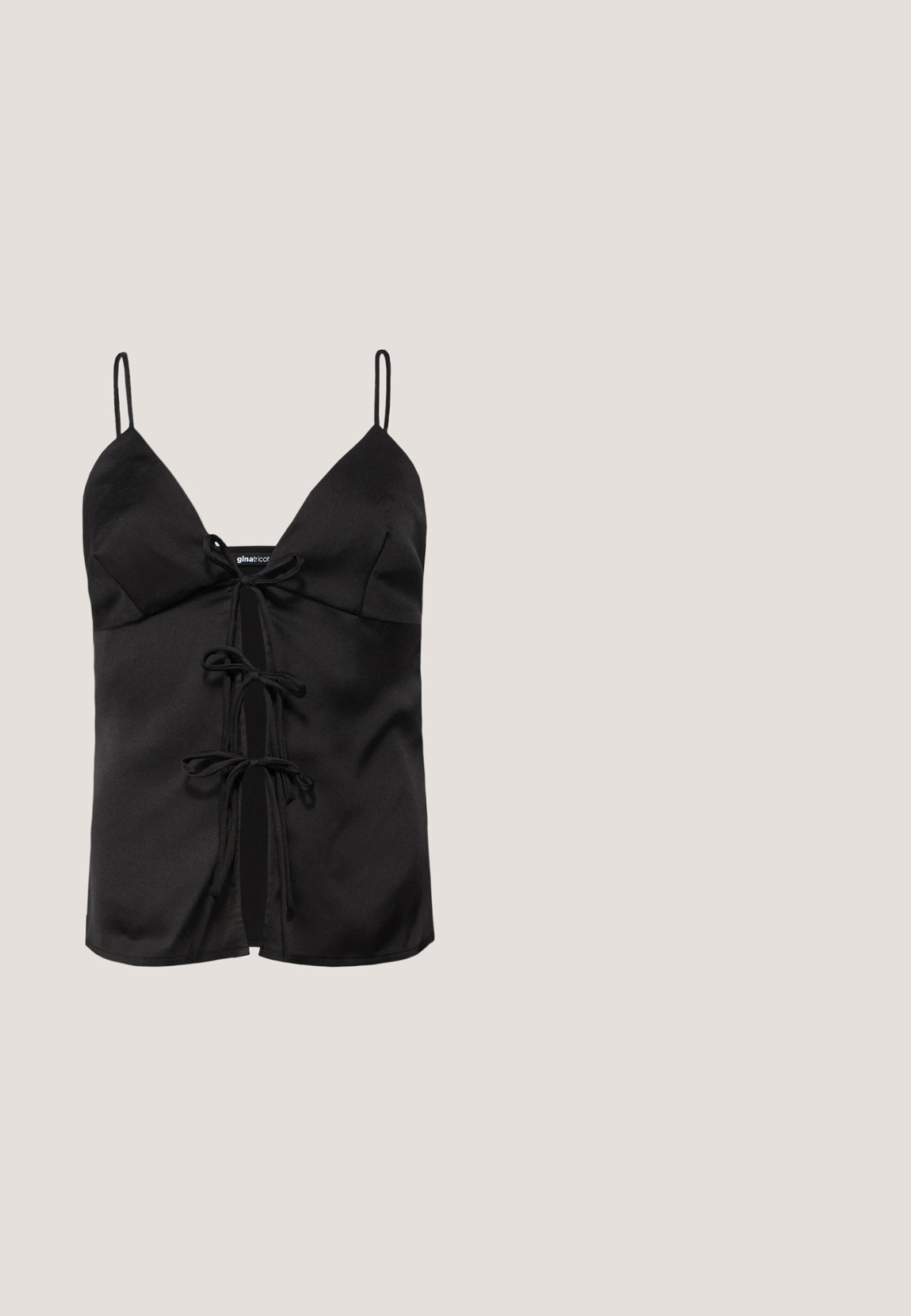 Sort satin camisole-top med tynde stropper, V-halsudskæring og et frontbånd med løkker og en central åbning. Glat tekstur.; Sorte læderbukser med slim fit, der har en frontlynlås, knaplukning og knapdetaljer på siderne. Glat tekstur.; Sort lakeret ankelstøvle med spids tå og en midt-højde blokhæl. Glat tekstur og minimalistisk design.; Store oversized solbriller i sort med gradient grå linser, rektangulær form, blank finish og en lille guld logo detalje på siden.; Blank sort håndtaske med tophåndtag, gyldent spænde og aftagelig skulderrem på ensartet lys baggrund.; Trelags guldkæde halskæde med cirkulære led og en lukkemekanisme, lagt fladt på en lys baggrund.