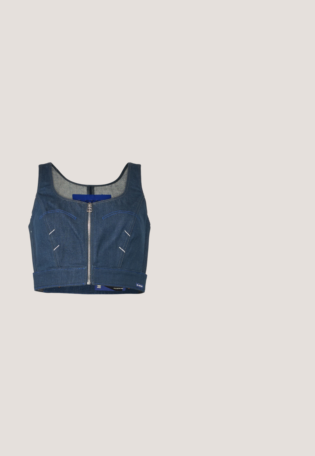 Tmavomodrý denimový crop top s okrúhlym výstrihom, predným zipsom a kontrastným prešívaním. Obsahuje dva predné vrecká s zakrivenými líniami.; Tmavomodrá, krátka áčková sukňa vyrobená z textúrovaného, ľahkého materiálu s hladkým pásom a bez vzorov alebo ozdôb.; Biela nízka plátenná teniska s hrubou platformovou podrážkou, šnurovaním vpredu a gumovou špičkou s textúrou, zobrazená z bočnej strany.; Ovládacie strieborné kovové okuliare oválneho tvaru s priehľadnými sklami, s dekoratívnymi bočnými akcentmi a čiernymi koncovkami na stranách rámu pre lepšie držanie a pohodlie.; Modrá denimová crossbody taška s nastaviteľným remienkom a malým kovovým logom vpredu, zobrazená na bielom pozadí.; Strieborné kruhové náušnice s hladkým, lesklým povrchom. Obľúbený tvar, vybavené bezpečným zapínaním. Jednoduchý a elegantný dizajn.