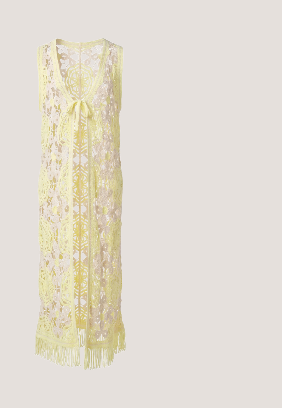 Mouwloze lange gele gehaakte vest met bloemmotieven, sluiting met strik aan de voorkant en franjes aan de zoom.; Witte blouse met bloemenborduursel, knoopsluiting, hoge hals en pofmouwen. Gemaakt van gestructureerde stof met een zachte, lichte textuur.; Witte enkellange rok met bloemige kanten patronen gerangschikt in vierkante panelen en een nauwsluitende tailleband.; Bruine suède enkellaarsjes met een puntige neus, middelgrote blokhak en minimale stiksels voor een strakke uitstraling.; Bruine leren handtas met geweven textuur, enkele handgreep en ritssluiting.; Gouden ketting met een fijne schakel, voorzien van een toggle-sluiting en een getextureerde ronde hanger. Glad afwerking, eenvoudig ontwerp.