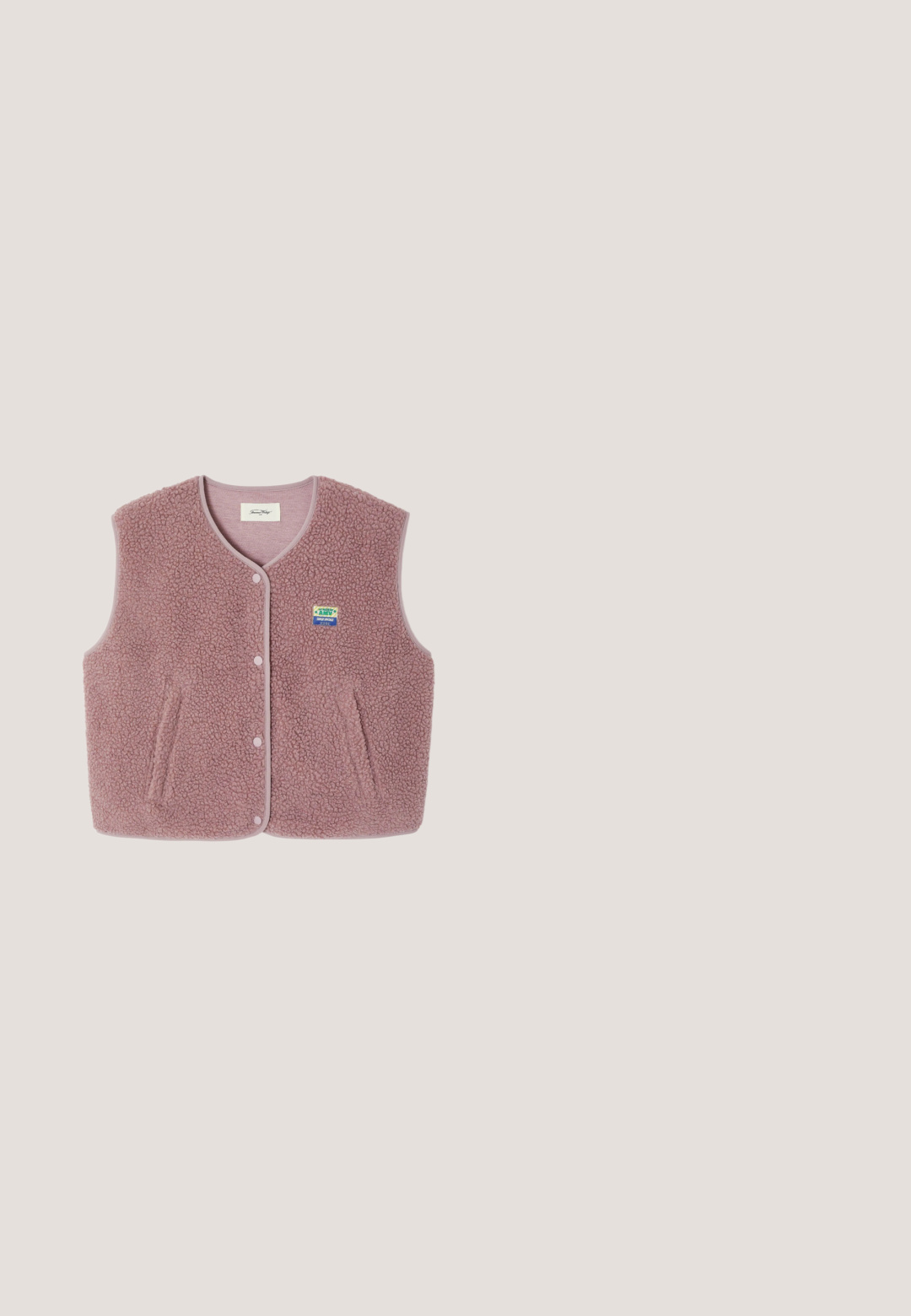 Mouwloos stofroze sherpa fleecevest met drukknoopsluiting, twee voorzakken en een kleine kleurrijke patch op de borst.; Lichtroze cropped top met korte mouwen en V-hals, met de tekst "Juicy" in strass-steentjes gecentreerd op de borst.; Roze sweatpants met een elastische tailleband, voorzien van decoratieve patches in ruitvorm aan de linkerkant en elastische boorden bij de enkel.; Roze suède sneaker met witte hartaccent, vetersluiting en witte rubberen zool. Gladde textuur, ronde neus en contrasterende details.; Roze leren handtas met zwart MCM-logo patroon, gouden kettingdetail en verstelbare schouderband op witte achtergrond.; Gouden armband met roze, paarse en heldere edelstenen, voorzien van een kleine gouden sluiting en verstelbare ketting op een witte achtergrond.