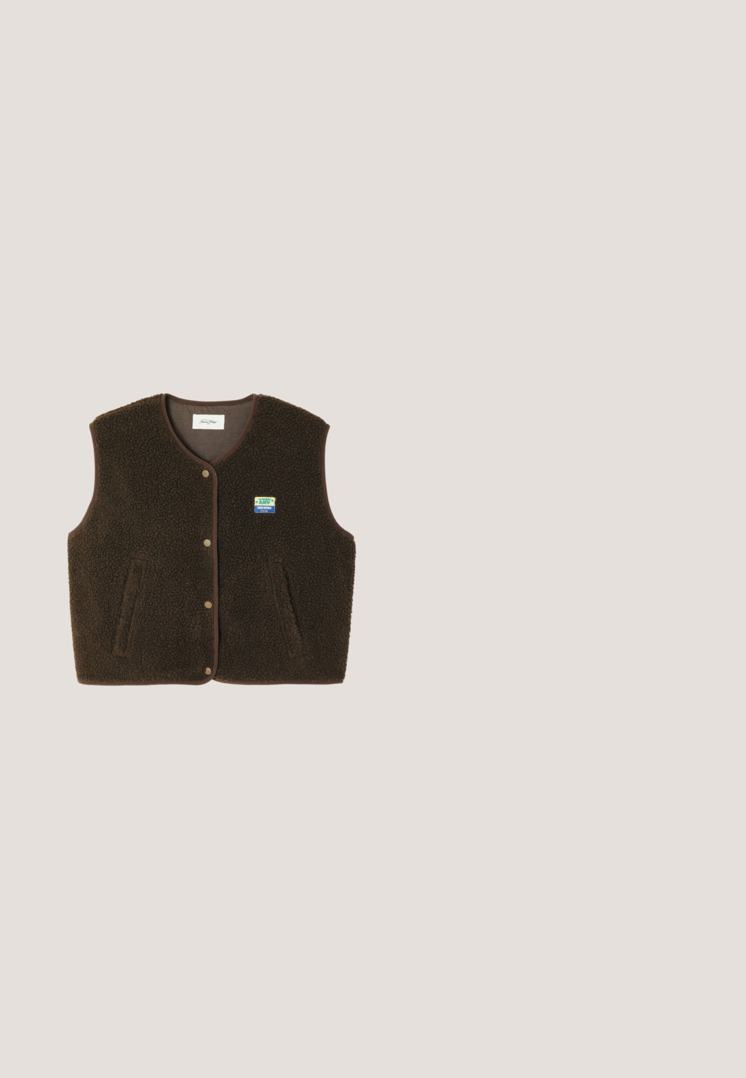 Bruine mouwloze fleecebodywarmer met drukknoopsluiting aan de voorkant, twee zijzakken en een kleine rechthoekige blauw-gele patch op de linkerborst.; Donkerbruine t-shirt met ronde hals van zachte gebreide stof met fijne ribstructuur.; Bruine brede pijpen broek met krijtstreep, riemlussen en voorplooien, plat uitgestald op een lichtgrijze achtergrond.; Zwarte leren enkelboot met elastische zijpanelen, ronde neus, contrasterende gele stiksels en een robuuste rubberen zool.; Rechthoekige bril met een schildpadpatroon, zwart kunststof montuur en transparante glazen. Voorzien van dunne pootjes en een lichte buiging aan de uiteinden.; Zachte donkerbruine leren handtas met een slungelige vorm en twee dunne schouderbandjes tegen een witte achtergrond.