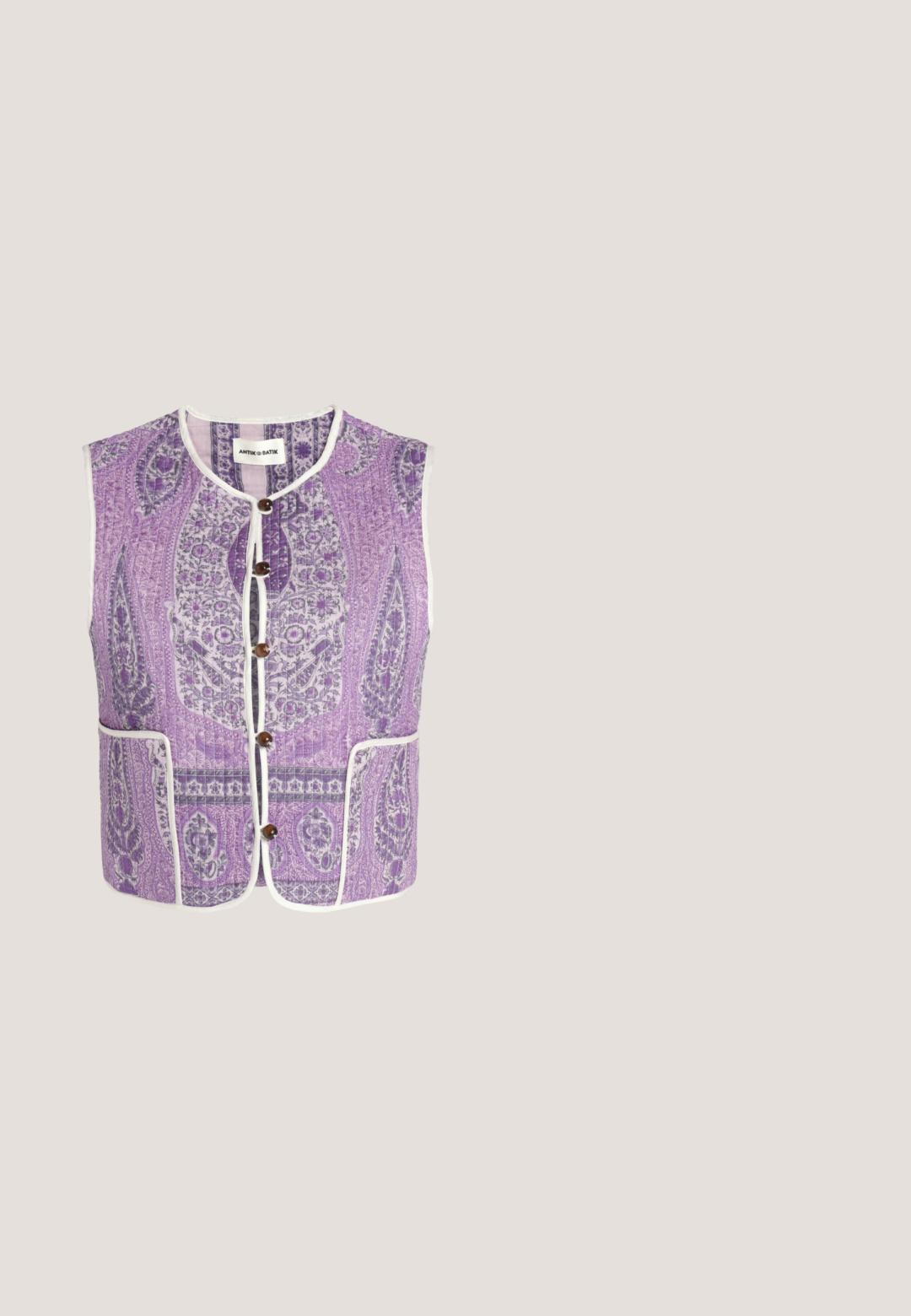 Veste matelassée sans manches avec motif floral paisley violet, bordure blanche, boutons marron, poches avant et encolure ronde.; Robe longue bleue à col halter avec motifs floraux et géométriques en crème, violet et vert, dotée d’un décolleté goutte d’eau et d’une taille cintrée.; Sandales à talons roses avec finition brillante, présentant des brides croisées et un nœud décoratif en matériau métallique. Bride de cheville ajustable.; Lunettes de soleil à monture dorée avec des verres dégradés roses et des branches texturées roses, posées en angle sur une surface blanche projetant des ombres douces.; Sac à main tissé rose vif avec deux poches avant, de grands boutons ronds et une poignée arrondie unique sur un fond clair uni.; Paire de petites boucles d'oreilles créoles en or avec un émail rose vif sur la moitié extérieure, présentées sur un fond blanc.