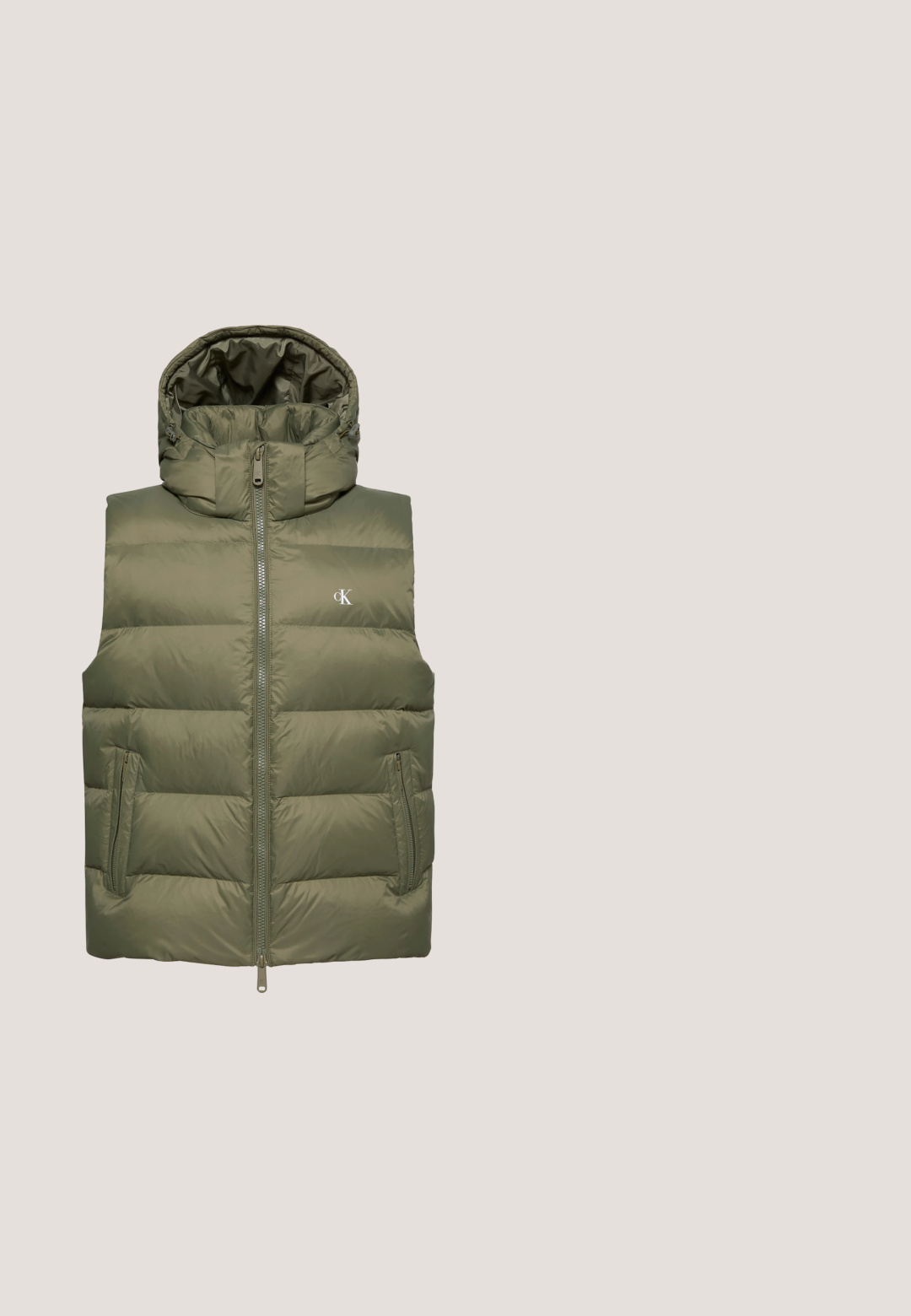 Chaleco acolchado sin mangas de color verde oliva con capucha, cremallera frontal, bolsillos con cremallera y pequeño logo blanco "cK" en el pecho.; Sudadera gris con capucha, bolsillo frontal, cordón y un pequeño logotipo rosa en el pecho. Tejido suave con puños y dobladillo acanalados.; Camiseta de manga corta verde oscura hecha de algodón, con un logo amarillo en la parte izquierda del pecho y un clásico cuello redondo.; Vaqueros de mezclilla azul claro con corte recto, diseño de cinco bolsillos y un sutil desgastado. Presentan un cierre de botón y pasadores para cinturón.; Zapatilla marrón de Calvin Klein con suela y cordones blancos, exhibida frente a una pared de bloques de vidrio y un suelo de hormigón.; Maletín de cuero negro texturizado con bolsillo frontal con cremallera y asas dobles, con un pequeño logo de Calvin Klein en la esquina inferior.