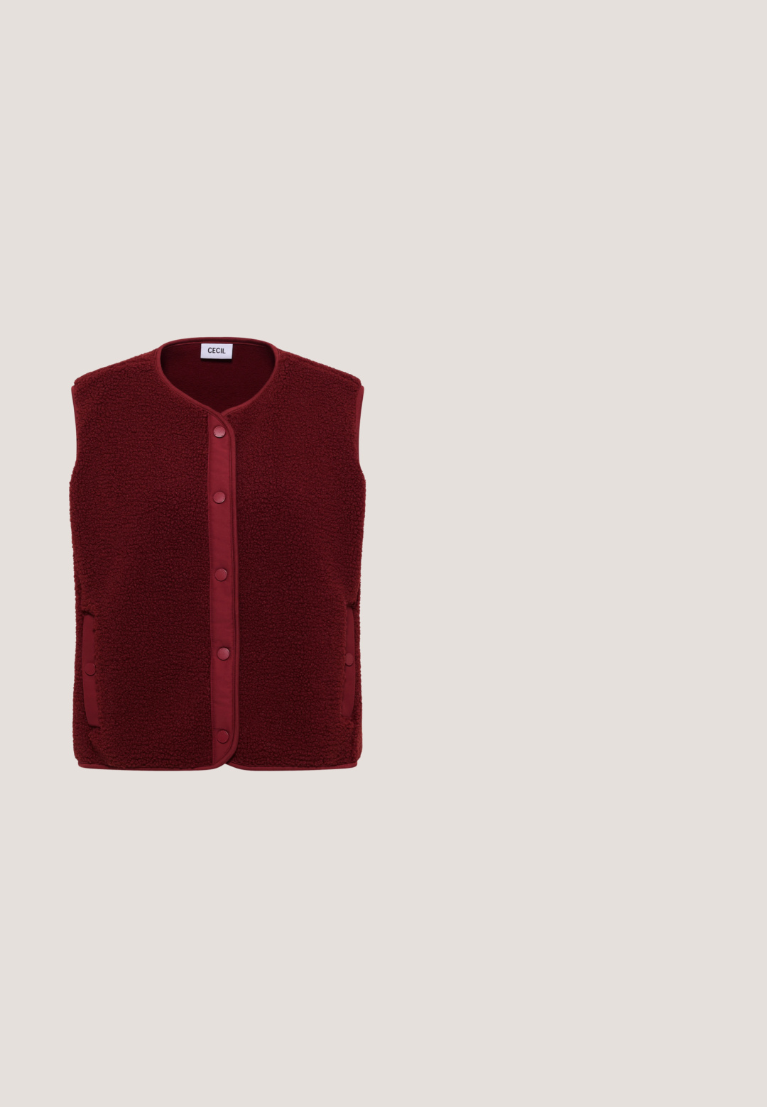 Ärmellose burgunderrote Fleeceweste mit Druckknöpfen vorne und Taschen auf beiden Seiten, innen am Kragen mit "CECIL" beschriftet.; Burgunderfarbenes Sweatshirt mit einem geometrischen weißen Sternmuster. Rippkragen und -bündchen. Weiche Textur und lockere Passform.; Bordeauxrote Jogginghose aus weichem Stoff mit einem Tunnelzugbund, schmaler Passform, elastischen Bündchen und ohne sichtbare Muster oder Akzente.; Rote Wildledersneaker mit einem plüschigen beigen Innenfutter, ausgestattet mit einer klobigen weißen Sohle mit strukturiertem Finish und einem auffälligen runden Logo an der Seite.; Dunkellila strukturierte Tragetasche mit zwei Griffen und einer Klappe oben, mit goldenem Wittchen-Logo unten in der Mitte.; Goldfarbener Ring mit glatter Band und einem runden, facettierten rosa Stein, der in einer sechsprongigen Fassung eingesetzt ist. Innen im Band mit "Ag 925" markiert.