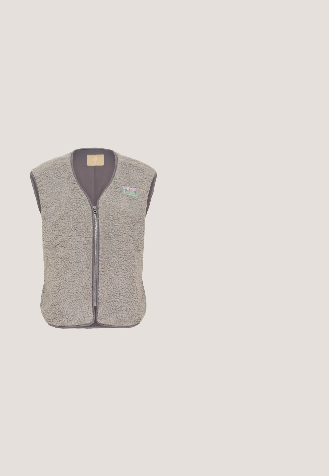 Chaleco sin mangas de sherpa gris claro con cremallera frontal y pequeño parche colorido en la parte superior izquierda del pecho.; Sudadera con capucha forrada de pelaje marrón, con cremallera de medio camino en la parte delantera, cordón con acentos metálicos, y puños y borde acanalados. Cuenta con un bolsillo frontal.; Top blanco de manga larga hecho de una tela ligera, que presenta una silueta ajustada y una textura suave con un escote redondo y sin acentos visibles.; Pantalones de pierna ancha beige con una tela suave y texturizada y una cinturilla elástica, diseñados para ofrecer comodidad y facilidad de movimiento.; Botines beige con suave forro de piel sintética, punta redonda y detalles en marrón en los cordones. Presentan paneles laterales texturizados y una suela gruesa.; Bolso bandolera taupe acolchado en forma de media luna con correa ajustable y cierre de cremallera, con el logo "GOT BAG." en el frente.