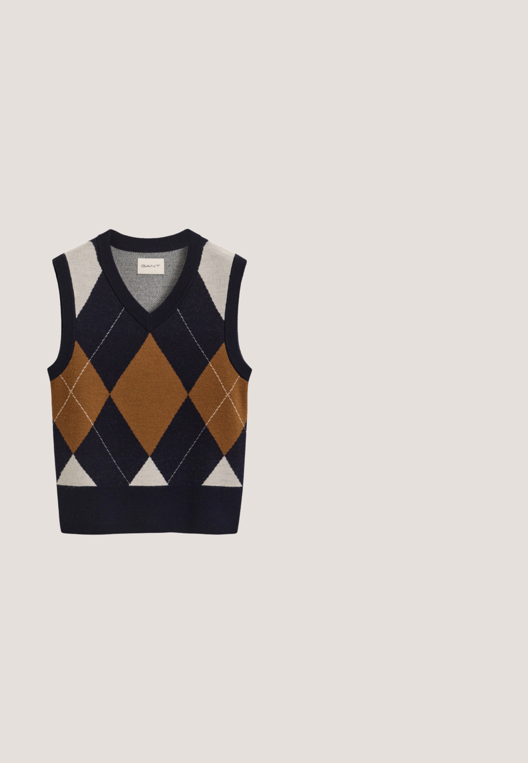 Mouwloze gebreide vest met V-hals, met een groot bruin, marineblauw en crème argyle-patroon aan de voorkant.; Wit overhemd met lange mouwen, knopen, een puntige kraag en een klein Calvin Klein-logo op het linker borstzakje.; Marineblauwe geplooide rok met een gestructureerd ontwerp, elastische tailleband met "LACOSTE" merknaam en een gladde stof.; Bruine leren loafer met een afgeronde neus, decoratief riempje en klein hakje. Gladde textuur, subtiele stiknaden en gouden accenten.; Marineblauwe zijden sjaal met geometrische rode en witte patronen, polkadots en een ankerontwerp in één hoek. Vierkante vorm, gladde textuur.; Bruine leren handtas met dubbele handvatten, afneembare schouderband, goudkleurige "MK" charme en het Michael Kors logo op de voorkant.