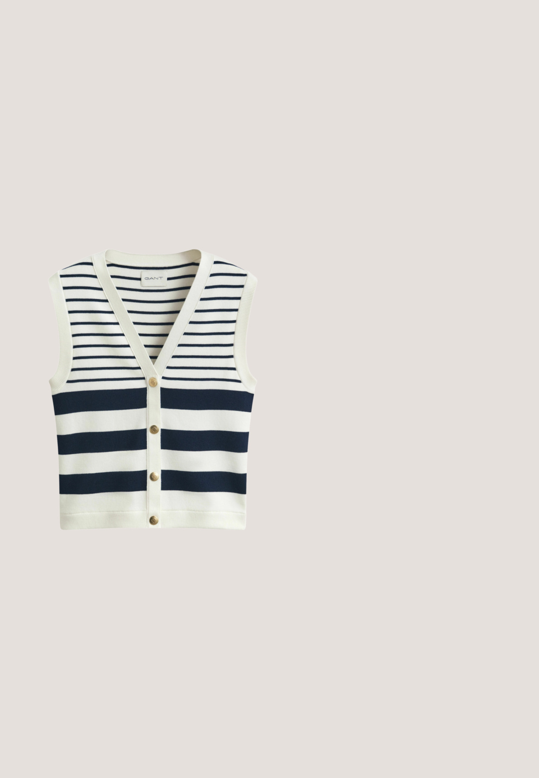 Gilet sans manches en maille avec rayures horizontales bleu marine et blanches, col en V et quatre boutons dorés sur le devant.; Polo à manches courtes blanc avec des rayures horizontales bleu marine, doté d'un col blanc et de trois boutons dorés à l'avant.; Pantalon large taille haute bleu marine avec de fines plis verticaux et une ceinture élastique sur un fond clair.; Mocassins en daim bleu marine avec un bout pointu et un nœud décoratif sur le dessus. Semelle plate couleur beige avec des détails de couture minimalistes.; Petit sac fourre-tout bleu marine avec de larges poignées rayées verticales crème et bleu marine, ainsi qu'une bandoulière adjustable bleu marine, sur fond blanc.; Boucles d'oreilles créoles en or et bleu marine avec des accents torsadés en or sur un fond blanc, présentées côte à côte.