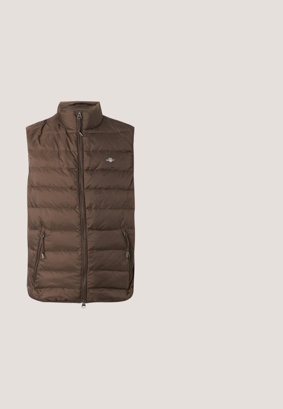 Chaleco acolchado marrón sin mangas con cremallera frontal, dos bolsillos laterales con cremallera y un pequeño logo bordado en el pecho.; Sudadera blanca con escote redondo, puños y dobladillo de canalé, que presenta una letra "G" en navidad bordada en el lado izquierdo del pecho.; Camiseta de manga corta color verde oliva con cuello redondo y pequeño logo negro de Calvin Klein en el lado izquierdo del pecho.; Pantalones de chándal grises hechos de una tela suave, con una cinturilla elástica y piernas ajustadas con puños elásticos. Detalle sutil del logo en una pierna.; Zapatillas de piel de ante beige con suela de goma blanca, que presentan un acento en el talón de color verde oscuro y un sutil logo en el lateral.; Bolso de tela acolchada de color verde olivo con una correa negra, que cuenta con un cierre superior de cremallera y un bolsillo exterior con cremallera adornado con patrones geométricos.