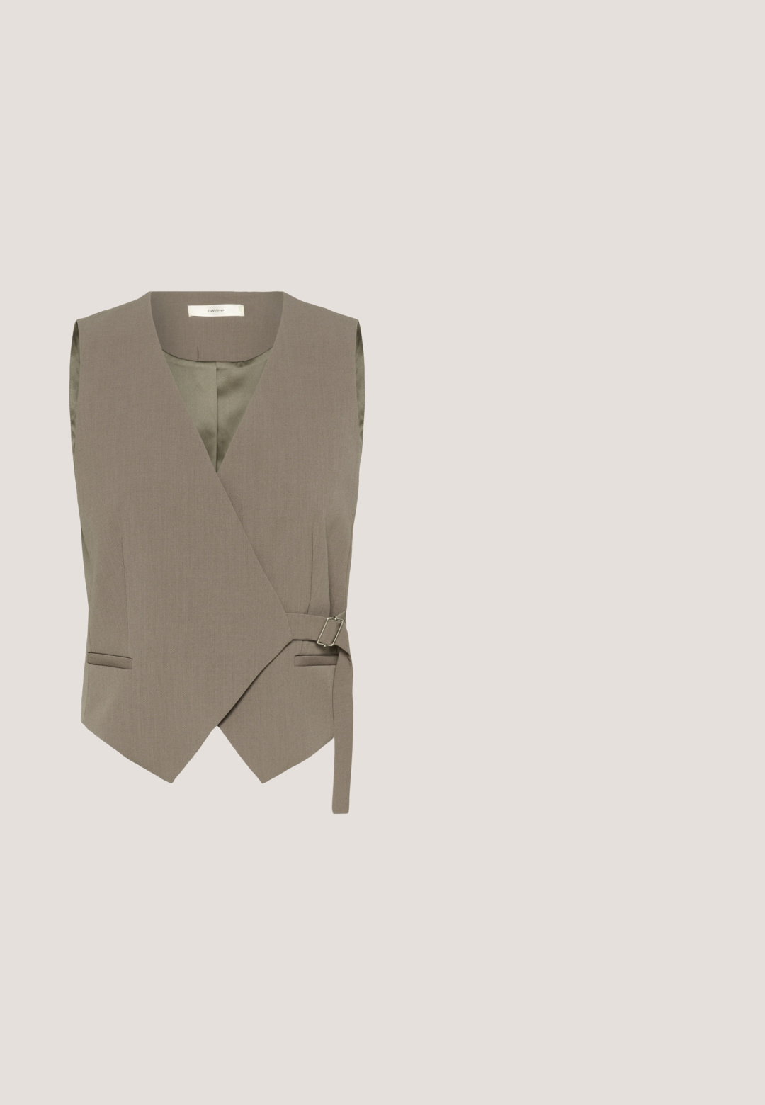 Taupekleurig wikkelvest met twee zijzakken, een zilverkleurige gesp en een gladde voering. Heeft een diepe V-hals en een mouwloos ontwerp.; Grijze geblokte blouse met driekwart pofmouwen, ronde hals en gestructureerde stof. Het patroon bestaat uit kleine vierkanten van verschillende groottes.; Bruine broek met hoge taille en wijd uitlopende pijpen, voorzien van plooien en elastische boorden bij de enkels, met een verborgen sluiting aan de voorkant.; Beige suède muil met open neus, korte zwarte kittenhak en een open achterkant, weergegeven vanaf de zijkant op een witte achtergrond.; Donkerbruine zachte leren boodschappentas met twee lange handvatten en een verstelbare schouderriem op een witte achtergrond.; Gouden open ring met twee grote gladde zwarte ovale stenen aan elk uiteinde, gepolijst en reflecterend tegen een witte achtergrond.