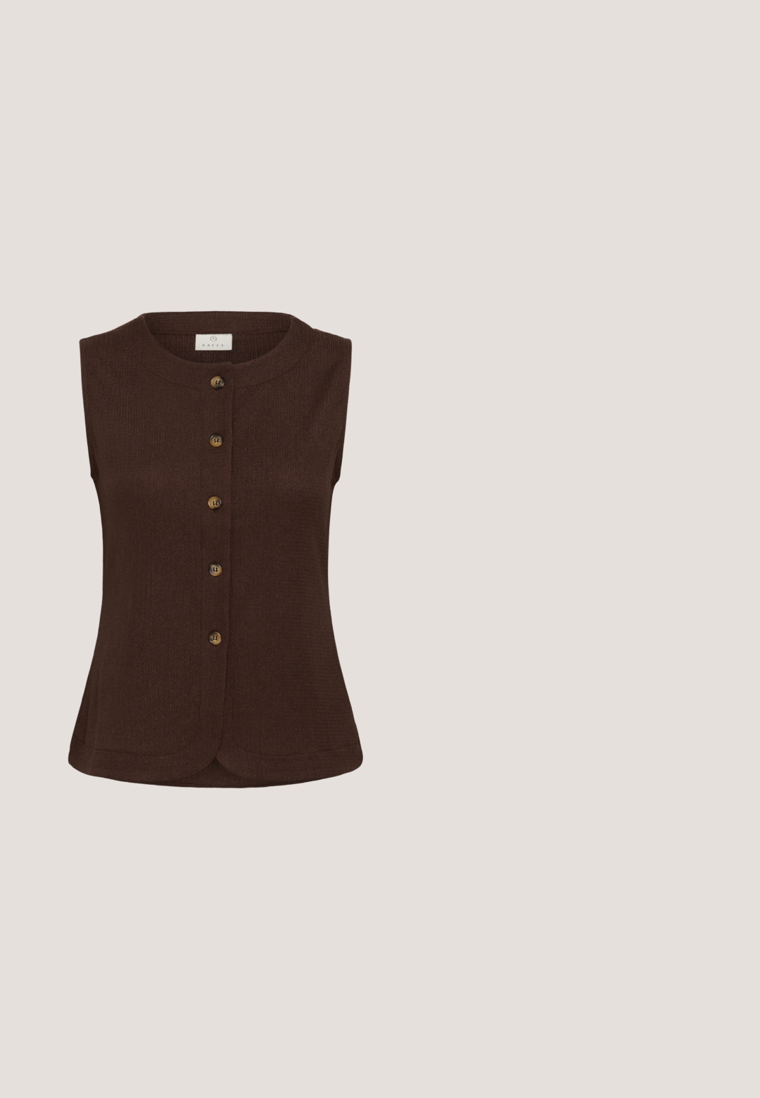 Chaleco sin mangas color marrón oscuro con cierre de botones, escote redondo y seis botones de madera en la parte delantera.; Blusa crema fabricada en tejido ligero, con un frente con volantes, cuello alto, mangas cortas y cierre de botones.; Pantalones cortos marrones hasta la rodilla, hechos a medida, con trabillas para cinturón y cremallera frontal, con etiqueta de la marca ICHI en el interior de la cintura.; Sandalia de charol burdeos con puntera abierta, dos tiras finas y tacón ancho sobre fondo blanco.; Pequeño bolso rectangular de cuero marrón oscuro con una sola correa y cierre de cremallera dorado.; Conjunto de joyería en tono dorado que incluye un collar con un colgante de lazo adornado con piedras de strass y una perla central, acompañado de pendientes a juego.