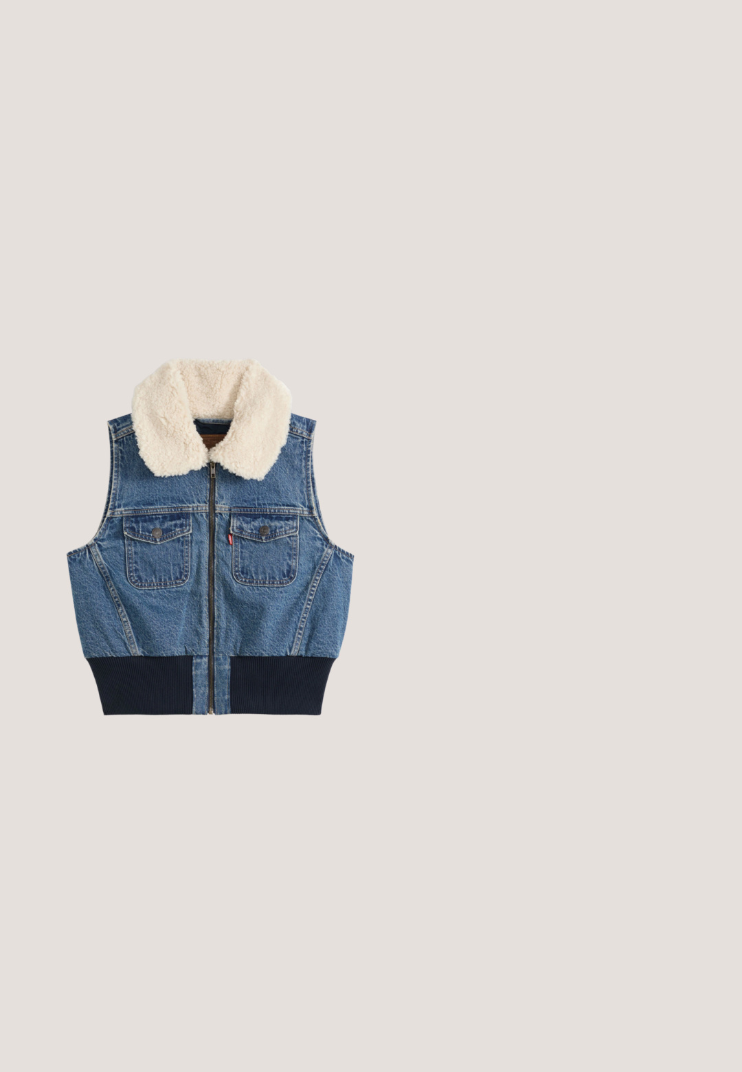 Chaleco vaquero con cremallera frontal, dos bolsillos en el pecho con botones, cinturilla acanalada y cuello de forro polar blanco sobre un fondo liso.; Camisa de manga larga azul claro con rayas verticales blancas, dos bolsillos en el pecho y botones marrones en la parte delantera. Tejido suave con una textura lisa.; Pantalones rectos de color azul claro, confeccionados en una tela suave, con frontal plano, bolsillos laterales y una cinturilla ajustada.; Zapato deportivo marrón con detalles de malla, parte superior de ante texturizado, cuello acolchado y suela de goma con un acento blanco en el talón.; Bolso tote azul marino con estampados de flores blancas, diseño elegante, material sintético, dos asas resistentes y superficie texturizada.; Pendientes en forma de corazón de oro, con una superficie lisa y un borde de cuentas. El diseño es simétrico y presenta un acabado brillante.