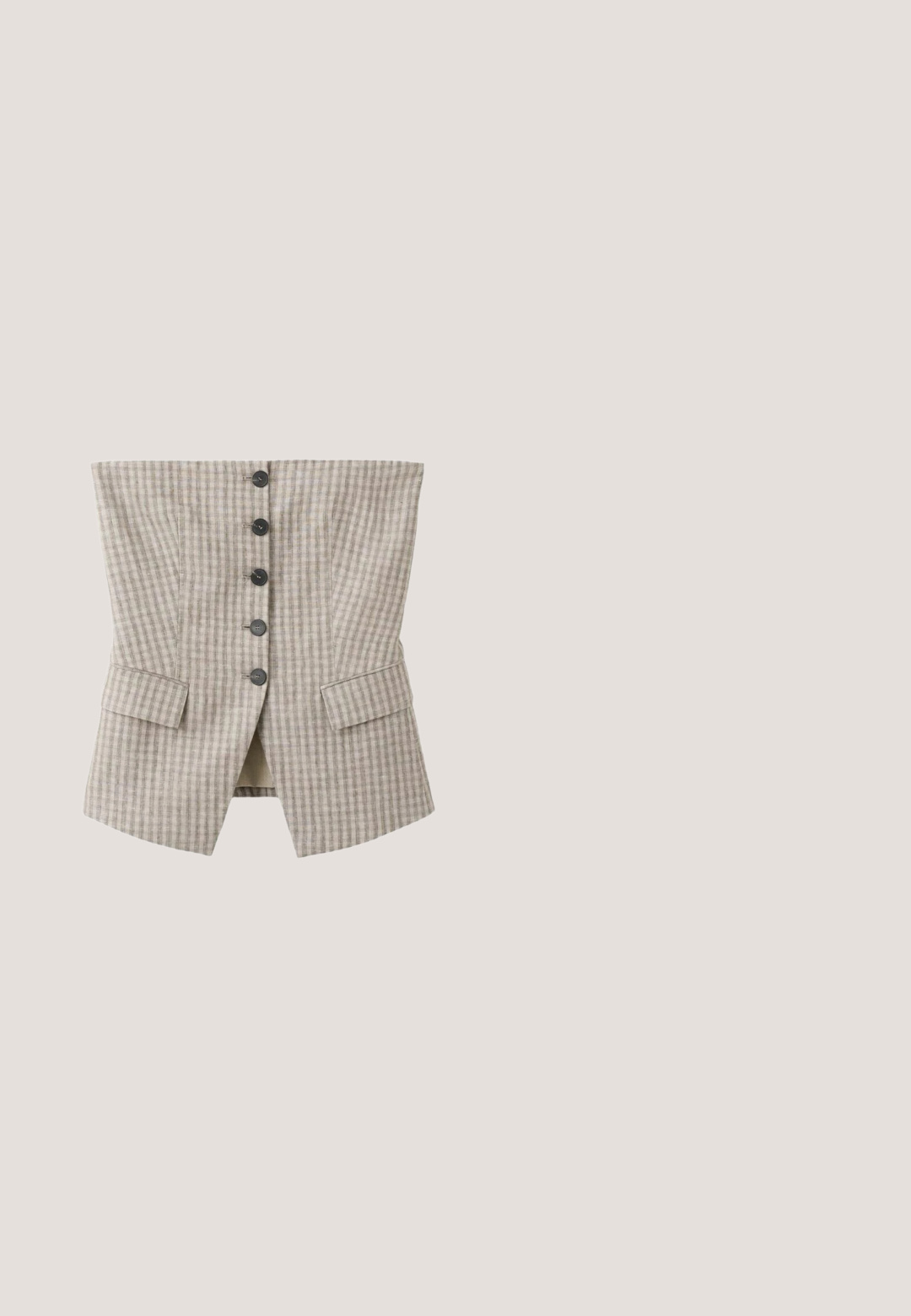 Gilet style corset à carreaux beige et gris avec cinq boutons noirs au centre et deux poches à rabat près du bas.; Haut court en lin marron sans manches avec encolure ronde, coupe ample et ourlet droit.; Ceinture de pantalon en tissu de lin beige avec un cordon de serrage noué, centré en haut.; Sandale slide en daim marron avec deux boucles argentées ajustables, semelle intérieure en liège et semelle noire texturée sur fond blanc.; Lunettes de soleil rondes avec monture écaille de tortue et verres teintés marron reposant sur une surface blanche.; Sac fourre-tout tissé marron foncé avec deux bretelles et un pompon décoratif avec de petits coquillages suspendu à une bretelle.