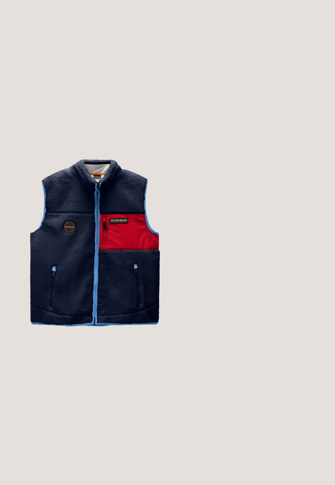 Donkerblauwe fleecevest met lichtblauwe afwerking, rode rits borstzak, twee onderste ritssluiting zakken en een klein rond logo aan de linkerkant.; Zwarte pullover hoodie met vooraan trekkoorden en klein rood-wit vlaglogo op de linkerborst, lange mouwen en geribbelde boorden en zoom.; Marineblauw polohemd met korte mouwen, een twee-knopsbies en een klein wit logo op de linkerborst.; Marineblauwe joggingbroek met elastische tailleband, trekkoord, zijzakken, geribbelde boorden en een klein Noors vlaglogo op de rechterdij.; Zwarte instapsneaker met witte zool zwevend boven een beige tapijt, naast een houten salontafel met gestapelde boeken, in een moderne woonkamer.; Compact, rechthoekig etui in marineblauw met een voorvak met rits en zwarte ritstrekkers, voorzien van een klein lichtgrijs geometrisch logo.