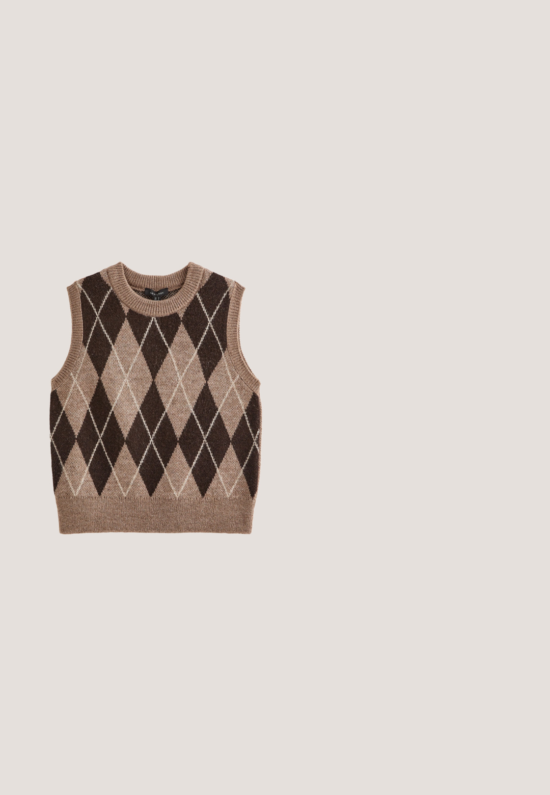 Chaleco de punto sin mangas con patrón de rombos argyle en marrón y beige, con cuello, sisas y dobladillo acanalados.; Cárdigan recortado beige con un tejido texturizado y un sutil brillo. Presenta botones plateados y dos bolsillos frontales. Cuello redondo.; Blusa blanca de botón con cuello voluminoso, rayas verticales y tejido texturizado. Presenta mangas abullonadas con elástico y adornos de encaje.; Falda midi plisada beige confeccionada en un suave material similar a la ante, con cintura con cinturón y pliegues verticales que aportan textura y movimiento.; Zapato Oxford brogue de cuero marrón con detalles de ala, perforaciones, cordones y tacón bajo apilado sobre fondo blanco.; Bolso de mano de cuero marrón con asa superior y cierre redondo dorado con giro en la solapa frontal.