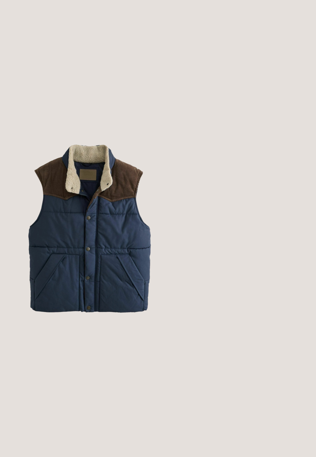 Mørkeblå vatteret vest med brun fløjls skulderstykke, frontknapper, skrå lommer og cremefarvet sherpa-foring på kraven.; Langærmet blå pullover med ribbet høj krave og kort lynlås i midten foran.; Mørkeblå langærmet henley skjorte med fire knapper og ribbet tekstur, der har rund halsudskæring og manchetter.; Blå denim jeans med lige ben-design, der har en front knaplukning, bæltestropper og klassisk fem-lomme styling.; Mørkeblå ruskindssneakers med rund tå, tonede snørebånd og gummisål. Har en glat læderdetalje ved hælen og sidelister.; Sort lærredstaske med to lange brune læder skulderstropper og en stor frontlomme.
