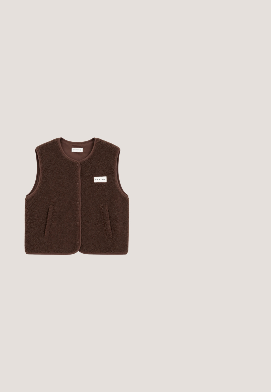 Gilet sans manches en polaire marron avec boutons-pression à l'avant, deux poches latérales et une petite étiquette rectangulaire "OH APRIL" sur la poitrine.; Haut à col roulé gris à manches longues, en tissu texturé, présentant un design ajusté et un motif ton sur ton subtil, avec un col haut bien ajusté.; Pantalon large en satin marron foncé avec taille élastique et bas élastiques froncés aux chevilles.; Bottine en daim marron avec un bout pointu et un talon carré. Présente des détails cousus et une languette à l'arrière pour un enfilage facile.; Lunettes de soleil écaille de tortue marron avec des verres ovales, dotées d'une fine monture et d'un petit accent métallique sur le côté. Fini texturé et poli.; Sac à main en daim marron au design structuré, doté d'une sangle fine mise en valeur par une boucle, et de deux poignées arrondies en haut.