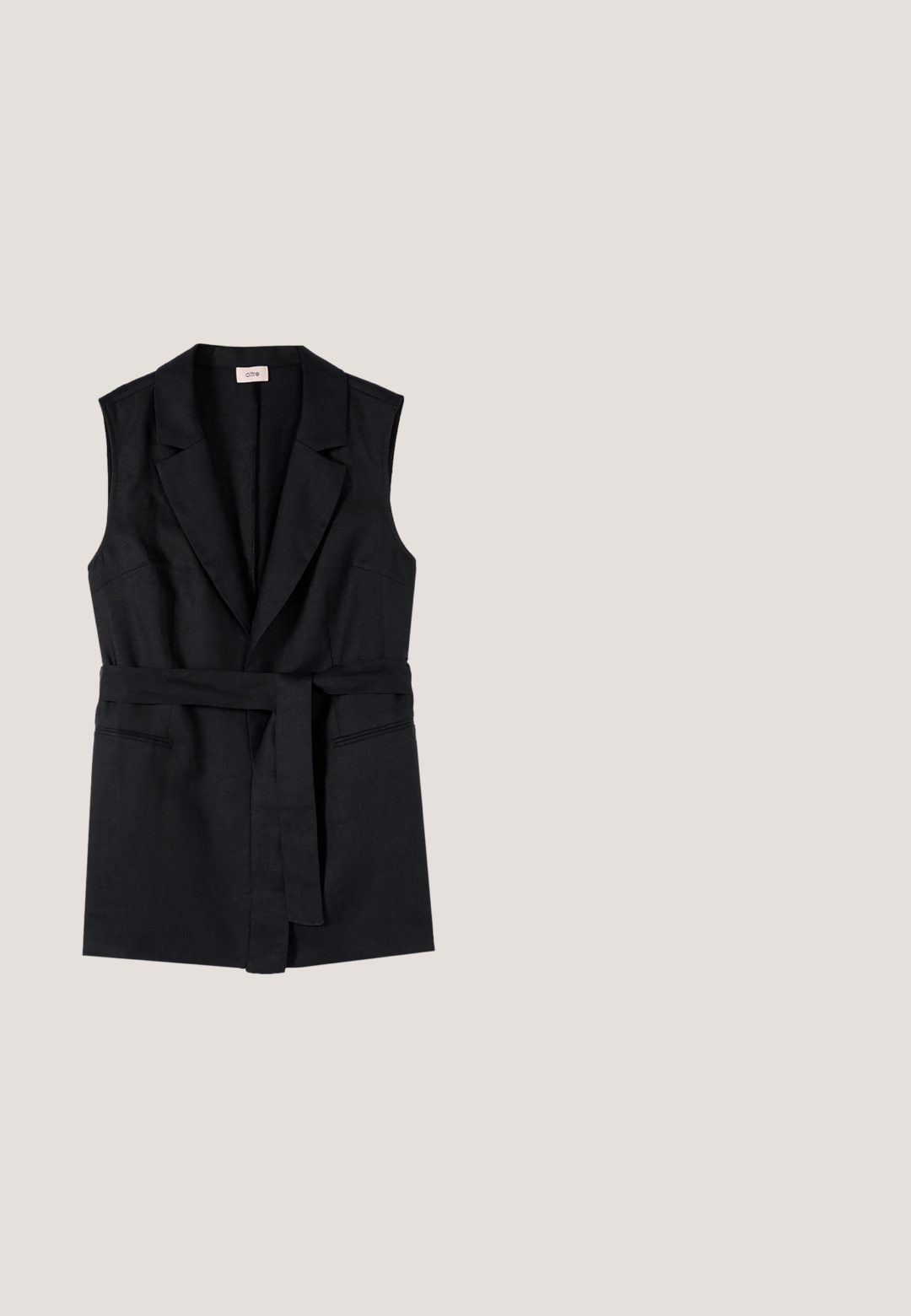 Sort ærmeløs blazer med reverskrave og bælte i samme stof bundet i taljen, med to horisontale skrålommer.; Ærmeløs haltertop med sorte, hvide og beige lodrette stammeinspirerede striber og dyb V-hals.; Hvide bukser med lodrette sorte og grå geometriske striber, elastisk talje og elastiske, rynkede manchetter ved anklerne.; Sort skridsandal med to guldspænder, glat tekstureret materiale, flad sål og et minimalistisk design.; Sorte ovale solbriller med brune tonede linser og tynde sorte arme, vist mod en hvid baggrund.; Vævet stråtaske med sort læderforlomme og nittebesatte sorte læderhåndtag, der strækker sig neden for taskens kant.