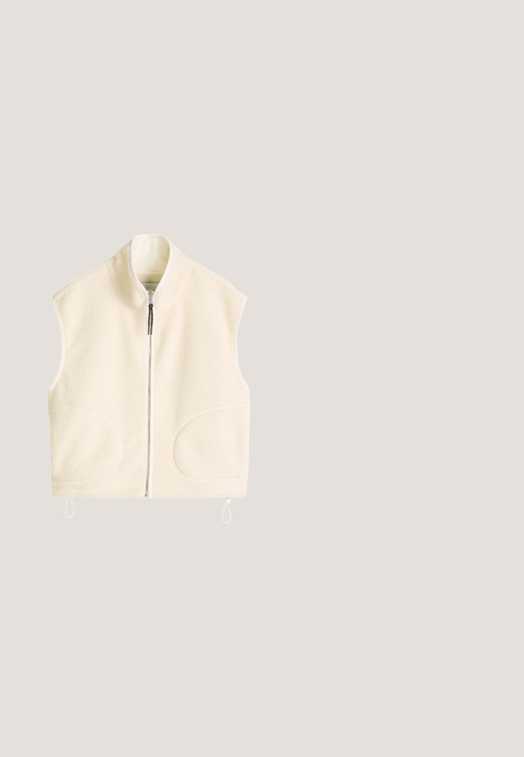 Roomkleurig mouwloos fleecevest met volledige rits aan de voorkant, hoge kraag en twee afgeronde voorzakken.; Rondhals, kortebloezende t-shirt van zachte, lichte katoen. Lichtbeige kleur met een relaxte pasvorm en een label aan de zijnaad.; Wijdvallende broek van crèmekleurig katoen met een knoop- en ritssluiting. Voorzien van een trekkoord in de taille en zijzakken.; Lichtbruine suède casual sneaker met witte stiksels, veters en een dunne gumzool, zichtbaar vanaf de linkerkant en met een geperst "HUGO"-logo.; Beige canvas draagtas met twee lange handvatten, een voorvak met klep en een minimalistisch ontwerp. Gladde textuur en eenvoudige, strakke lijnen.; Zilverkleurige ketting met een gladde, flexibele vorm. Voorzien van een karabijnhaak en een verstelbare ketting voor verschillende lengtes.