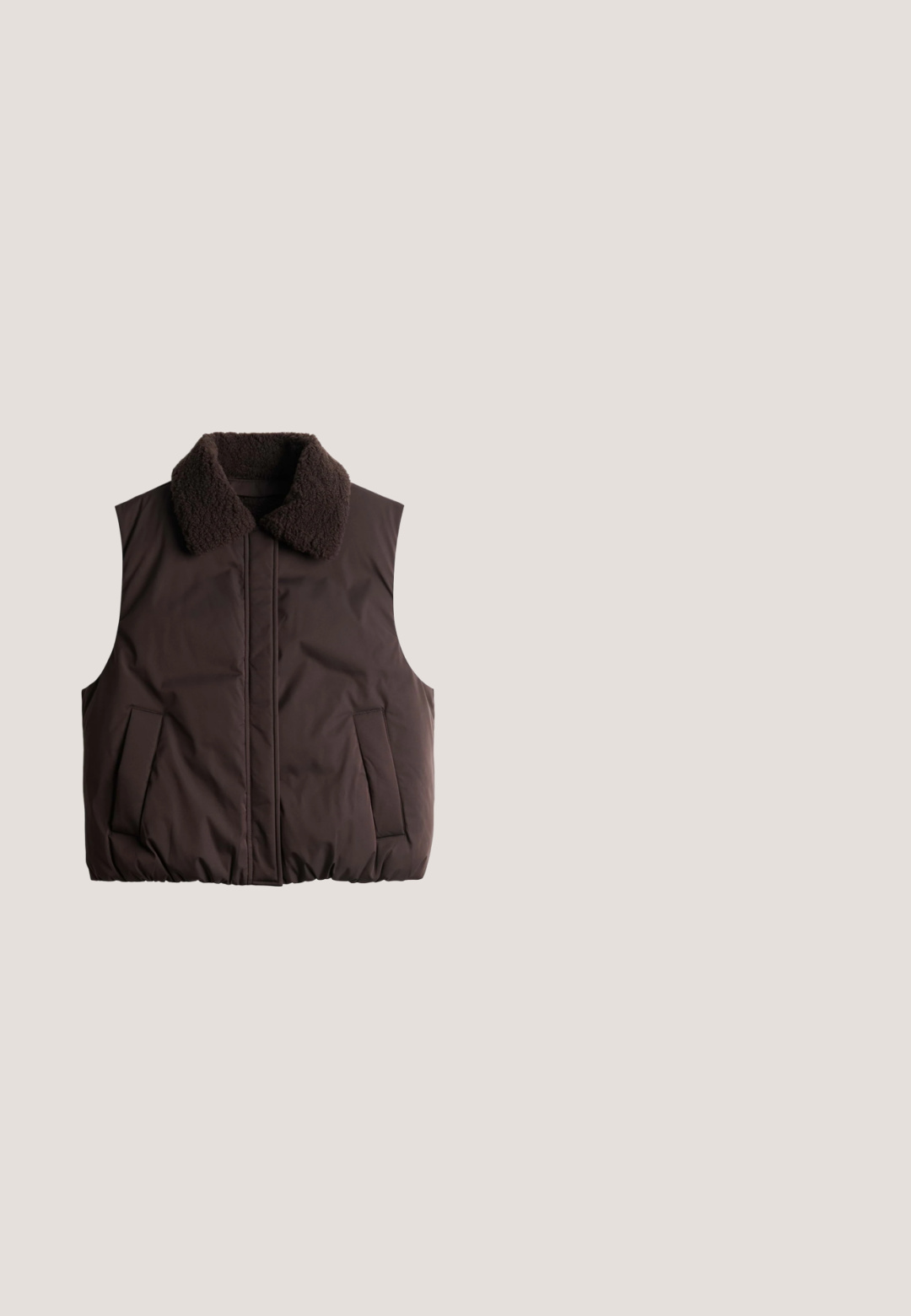 Dunkelbraune gesteppte ärmellose Weste mit dickem strukturiertem Kragen und Fronttaschen, flach auf weißem Hintergrund ausgelegt.; Brauner Fleece-Pullover mit weiß gesprenkeltem Muster, hohem Kragen, vorderem Halb-Reißverschluss und langen Ärmeln.; Langärmliges, dunkelviolettes Rollkragenshirt mit glatter Textur, flach auf weißem Hintergrund dargestellt.; Braune Leggings mit hoher Taille und voller Länge, flachen Nähten und breitem Bund, für eine enganliegende Passform entworfen.; Brauner Wildleder-Sneaker mit beigen Schnürsenkeln und mehrfarbigen Perlen, mit cremefarbenem Lammfellfutter und Gummisohle.; Braune strukturierte Tragetasche mit zwei Schulterriemen und Seitentaschen, dargestellt auf weißem Hintergrund.