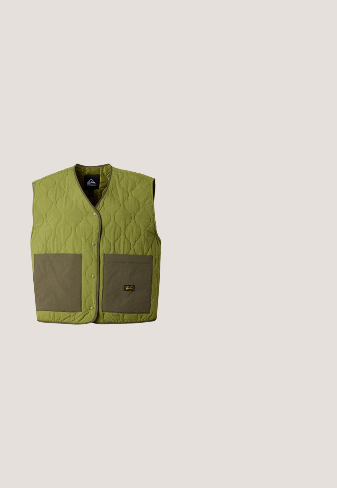Gewatteerd mouwloos vest in lichtgroen met twee grote olijfgroene voorzakken en drukknopsluiting.; Sweater met lange mouwen met een olijfgroene bovenkant, crème onderste deel en horizontale roze, oranje, gele en blauwe strepen over de borst en mouwen.; Lichtblauw cropped T-shirt met korte mouwen en een borstzakje met een witte zon en gezichtsgrafiek met de tekst "VOLCOM".; Korte beige shorts met een abstract patroon van zwarte vogels en blauwe sterren verspreid over de stof.; Persoon in lichtgroene en witte sneakers met witte veters en een spijkerbroek, staande op een lichtblauwe vloer.; Beige gaas draagtas met olijfgroene rand en handvatten, met het "RVCA"-logo over het middenpaneel op een effen achtergrond.