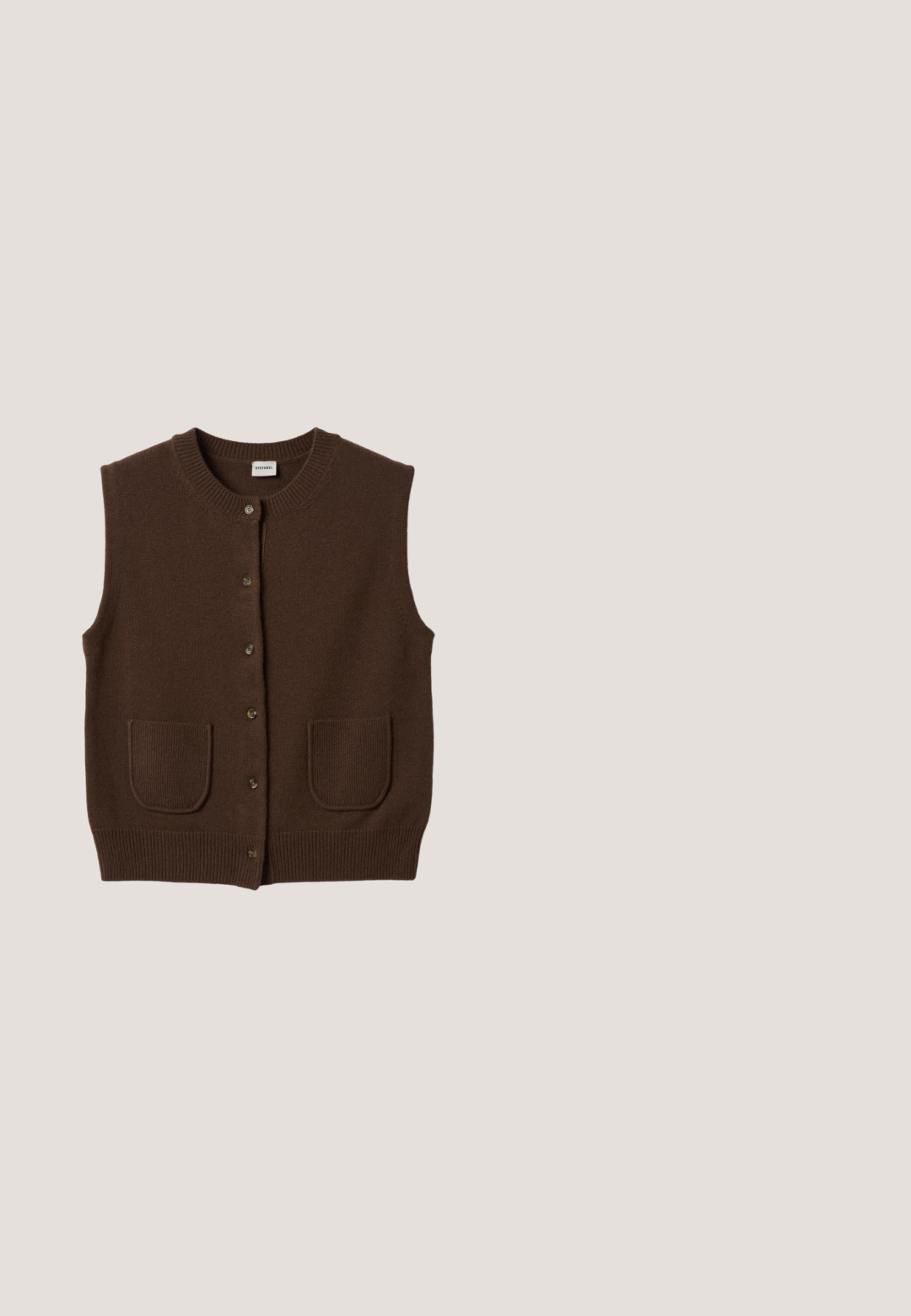 Bruine gebreide mouwloze cardigan met ronde hals, knoopsluiting aan de voorkant en twee opgezette voorzakken.; Zwarte langärmalige geribbelde t-shirt met een ronde halslijn en een nauwsluitend ontwerp. Gemaakt van een zachte katoenmateriaal, geschikt voor laagjes.; Bruine, op maat gemaakte broeken met plooien, wijde pasvorm, gladde textuur en een hoge taille, geschikt voor formele of casual gelegenheden.; Bruine suède instapschoenen met een gestikt moccasin-neus, platte zwarte rubberen zool en een decoratieve bovenband en detail.; Dikke donkerbruine rechthoekige zonnebril met licht afgeronde hoeken en lichtbruin getinte glazen op een witte achtergrond.; Zachte zwarte suède schoudertas met een enkele brede band en een afgeronde, licht slungelige vorm.