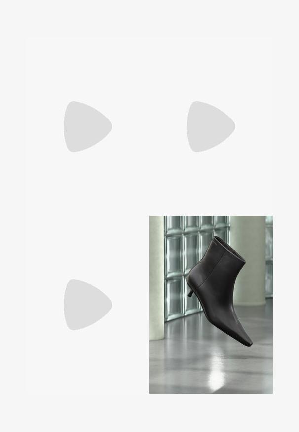 Good American FIT FOR SUCCESS BOOT - Ολόσωμη φόρμα - taupe; Μαύρο δερμάτινο μποτάκι με μυτερή μύτη και μικρό τακούνι, παρουσιάζεται μπροστά σε τοίχο από γυάλινα τετράγωνα και γυαλισμένο δάπεδο.; Σκούρα καφέ δερμάτινη τσάντα Calvin Klein με μακριές διπλές λαβές και ένα μικρό κρεμαστό λογότυπο κρεμασμένο από μία λαβή.; Ζευγάρι σκουλαρίκια κρίκοι σε χρυσό τόνο με μικρή ασημένια λεπτομέρεια σε κάθε έναν, εμφανίζονται πάνω σε ανοιχτό γκρι φόντο.