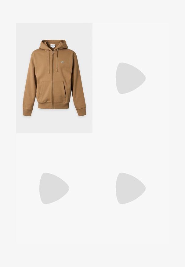 Hnedá mikina na zips s prednými vreckami, kapucňou so šnúrkou, rebrovanými manžetami a malým zeleným logom krokodíla na ľavej strane hrudníka.; Biela bavlnená tričko s krátkymi rukávmi, s kruhovým modro-oranžovým logom "Tennis Heritage" na ľavej hrudi.; Tmavohnedé bavlnené šortky s elastickým pásom a malým zeleno-bielym vyšívaným logom blízko dolného lemu na pravej nohe.; Béžová semišová tenisová obuv s gumovou podrážkou, šnurovacia, vznášajúca sa v interiéri na leštenej betónovej podlahe pri stene zo sklenených blokov.