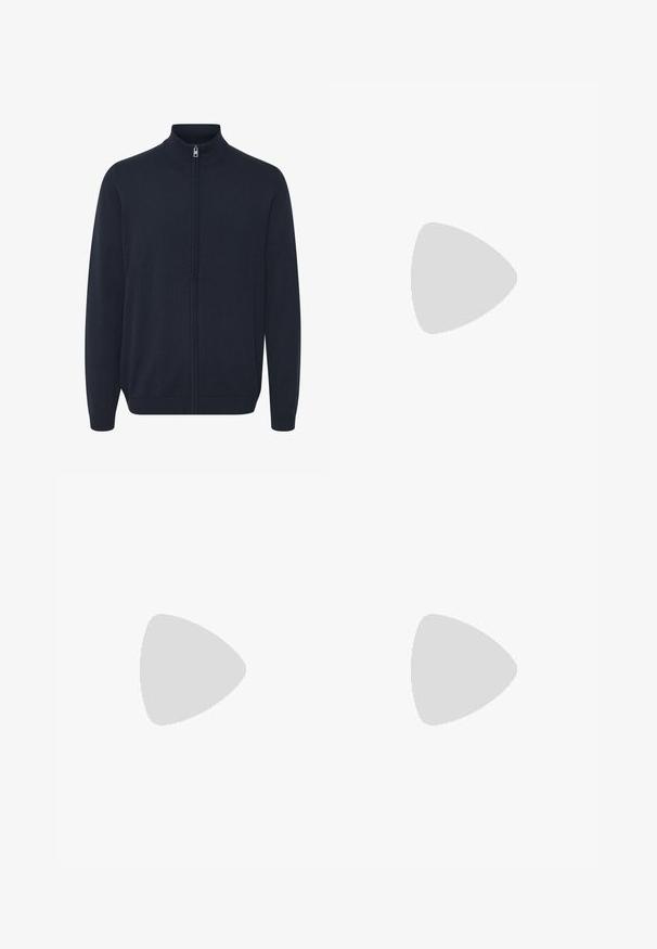 Tumesinine tõmblukuga cardigan, mis on valmistatud kudumiskangast. Omab kõrget kraed, pikki varrukaid ning soonikkoes mansette ja äärt. Sile tekstuur, minimalistlik disain.; Valge lühikeste varrukatega ümara kaelusega T-särk, mis on näidatud tagant lahti laotatult, väikese musta sildi jaotustükil kaelusel ja küljesõmmel.; Tumed sinised püksid siledast kangast, tavalise lõikega, viie tasku ja esise nupuga kinnitusega.; Noor mees tumedas nahktakšis ja teksades istub puidust pingil, kaldub ette, käed rüpes, vaatab valgel taustal küljele.