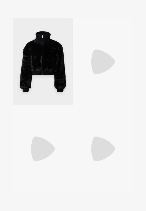 Veste en fausse fourrure noire courte avec un col montant, des poignets côtelés et une fermeture éclair à l'avant. Présente un design court et une texture douce.; Robe noire à manches longues avec un décolleté en V profond, présentant un tissu froncé et un détail en forme de trou de serrure au niveau de la poitrine, avec une jupe évasée.; Jambes portant des leggings côtelés foncés associés à des ballerines noires avec de petits détails en nœud sur fond blanc.; Petit sac à main noir brillant avec deux longues anses et des détails à cordon sur les côtés sur un fond clair uni.