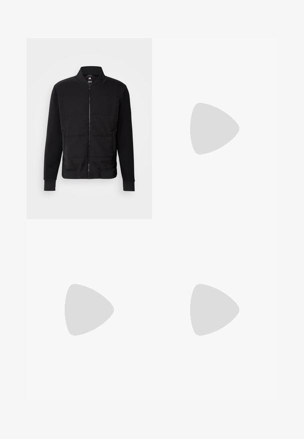 Schwarze Bomberjacke mit gepolstertem Oberkörper, festen Ärmeln, gerippten Bündchen und einem Frontreißverschluss. Material aus einer Mischung von synthetischen Stoffen und Baumwolle.; Beige T-Shirt mit kurzen Ärmeln aus Baumwolle, mit Rundhalsausschnitt, kontrastfarbigen Besätzen an den Ärmeln und einem Logolabel an der Seite.; Schwarze Hose aus glattem Stoff, mit geradem Schnitt, standardmäßigem Bund mit Knopfverschluss und ohne sichtbare Taschen oder Muster.; Schwarzer Sneaker mit niedrigem Schaft, strukturiertem Fersenbereich und weißer Sohle, schwebt über einem polierten Betonboden in der Nähe von Glassteinfenstern.