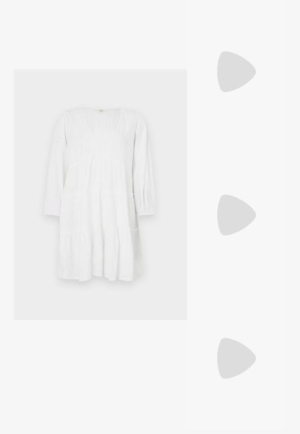 Witte, gelaagde jurk van lichtgewicht stof met lange mouwen, een diepe halslijn en subtiele verticale textuurdetails.; Zwarte wedge-sandalen met een geweven bandontwerp, voorzien van een textuur en een comfortabele zool. Geen zichtbare merknaam of versieringen.; Bruine schildpad zonnebril met een vintage cat-eye vorm en bruine lenzen. Heeft gebogen armen met rode accenten.; Geweven strooien tas met een brede, driehoekige vorm, zwarte leren handvatten met knopen en een open bovenkant. Natuurlijke stro kleur met textuur.