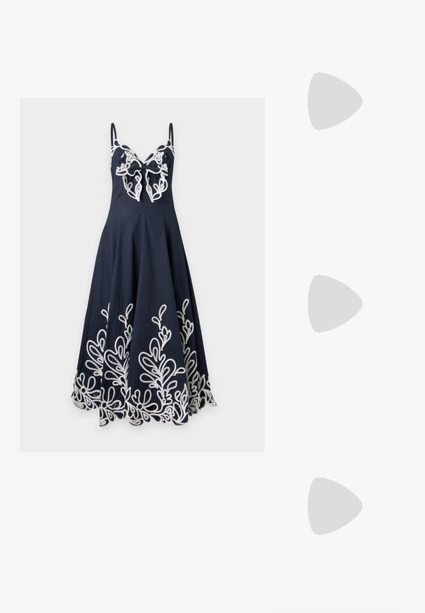 Robe bleu marine sans manches avec des détails en dentelle florale blanche le long de l'ourlet et un grand nœud en dentelle sur la poitrine.; Sandale à glissière plissée dorée avec un détail de nœud, bout ouvert et un talon bloc texturé. Présente une semelle plate et un intérieur lisse.; Sac cabas en paille tressée avec de larges anses en tissu tie-dye bleu clair et blanc et un grand nœud assorti en tissu à l'avant.; Boucles d'oreilles créoles en or massif avec un design tubulaire légèrement tordu et des fermoirs à tige sur un fond blanc.