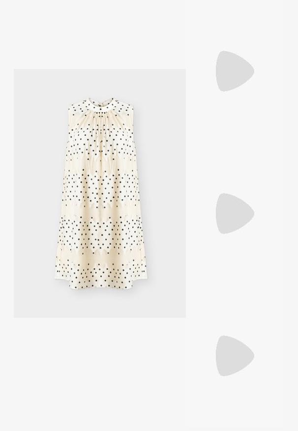 Robe crème sans manches à pois noirs, encolure froncée et silhouette droite et ample.; Jambes portant des leggings côtelés foncés associés à des ballerines noires avec de petits détails en nœud sur fond blanc.; Petit sac à main noir brillant avec deux longues anses et des détails à cordon sur les côtés sur un fond clair uni.; Boucles d'oreilles dorées avec une forme abstraite et organique, présentant une surface texturée et une fermeture à poussette.