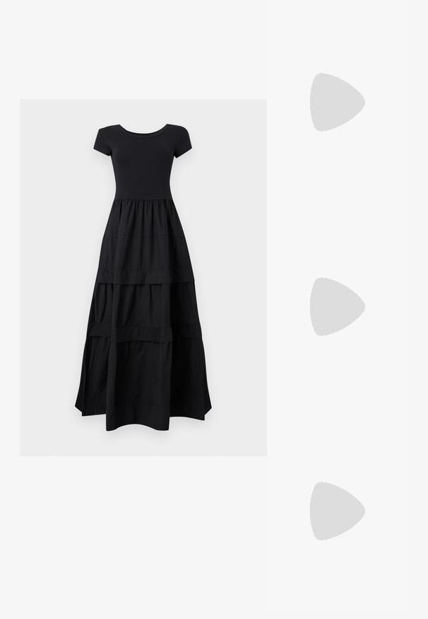 Robe maxi noire à manches courtes avec corsage cintré et jupe fluide à volants s'étendant jusqu'au sol sur un fond clair.; Jambes portant des leggings côtelés foncés associés à des ballerines noires avec de petits détails en nœud sur fond blanc.; Petit sac à main noir brillant avec deux longues anses et des détails à cordon sur les côtés sur un fond clair uni.; Boucles d'oreilles en métal argenté avec un design ondulé et sculptural, présentant une finition polie et des formes irrégulières, mettant en valeur une esthétique contemporaine.