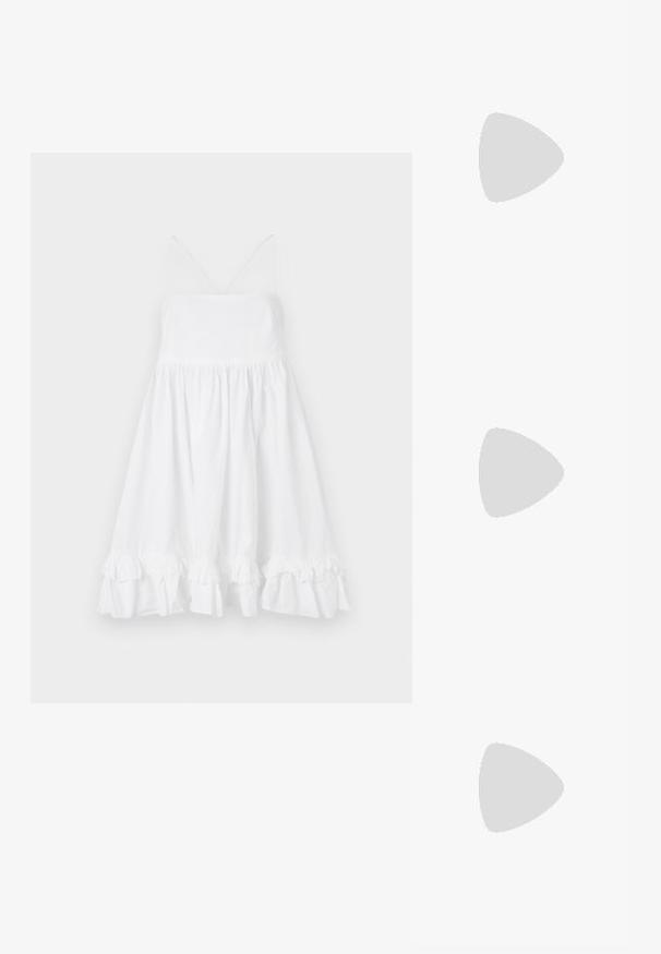 Robe blanche sans manches avec un corsage ajusté, une jupe évasée et un ourlet volanté. Fabriquée en tissu léger, elle présente des bretelles fines et un décolleté en V.; Mule sandale noire à bout ouvert avec fine bride en mesh et petit talon kitten sur fond uni gris clair.; Petit sac à main noir brillant avec deux longues anses et des détails à cordon sur les côtés sur un fond clair uni.; Paired boucles d'oreilles en métal doré poli de forme irrégulière avec un centre ouvert sur un fond blanc uni.