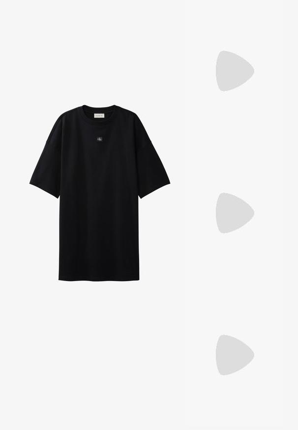 Μαύρο oversize T-shirt με κοντά μανίκια και μικρό ταμπελάκι με το λογότυπο Calvin Klein, τοποθετημένο στο κέντρο κάτω από το ντεκολτέ.; Μαύρο σουέτ sneaker με λευκές λεπτομέρειες και κορδόνια, με παχύ λευκό πάτο και αντίθετη ραφή, συνοδευόμενο από λευκή κάλτσα.; Διάφανα πλαστικά γυαλιά με τετράγωνους σκελετούς και διαφανείς φακούς, με χρυσές λεπτομέρειες στους βραχίονες για επιπλέον στυλ.; Μαύρη καπιτονέ τσάντα ώμου με έναν μόνο ιμάντα και ασημένια εξαρτήματα, σε συνδυασμό με ένα εφαρμοστό φόρεμα με σχέδιο tie-dye σε αποχρώσεις του μαύρου και του κρεμ.