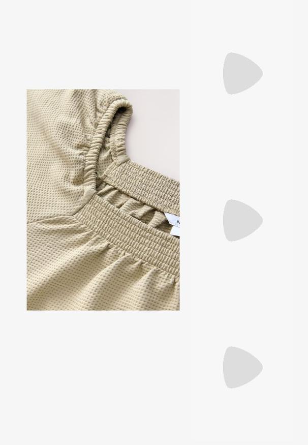 Haut beige clair avec un motif texturé en forme de grille, des poignets élastiqués et une taille froncée pour une coupe ajustée.; Sandale plate noire avec brides croisées, bride de cheville à boucle dorée et décoration de perles dorées sur la boucle de l'orteil.; Lunettes de soleil ovales noires avec des montures épaisses et des verres teintés foncés, posées sur une surface claire.; Sac à main en cuir tressé noir avec poignée courte et bandoulière amovible, présenté sur un fond clair uni.