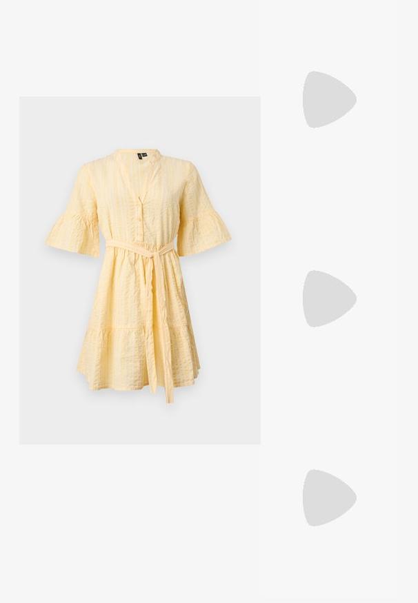 Robe jaune clair longueur genou avec manches évasées trois-quarts, boutons sur le devant, rayures verticales texturées et ceinture nouée à la taille.; Jambes portant des leggings côtelés foncés associés à des ballerines noires avec de petits détails en nœud sur fond blanc.; Petit sac à main noir brillant avec deux longues anses et des détails à cordon sur les côtés sur un fond clair uni.; Boucles d'oreilles dorées avec une forme abstraite et organique, présentant une surface texturée et une fermeture à poussette.