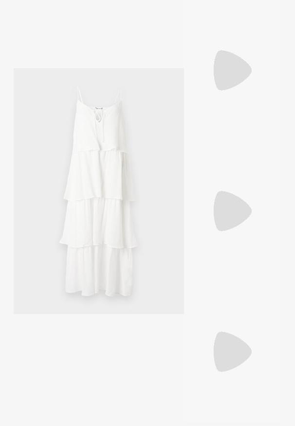 Robe blanche à volants en tissu texturé, avec de fines bretelles spaghetti et un détail noué au niveau du col.; Sandale noire en cuir à bout ouvert avec petit talon kitten, fine bride de cheville avec boucle dorée et accent décoratif doré sur la bride avant.; Petit sac à main noir brillant avec deux longues anses et des détails à cordon sur les côtés sur un fond clair uni.; Boucles d'oreilles en métal doré avec une forme lisse et arrondie et une finition polie. Design simple sans embellissements supplémentaires.