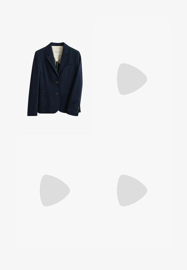 Marineblauer maßgeschneiderter Blazer mit zwei vorderen Knöpfen, zwei aufgesetzten Taschen unten, einer Brusttasche mit Paspelierung und Revers mit Kerbe.; Langärmlige weiße Bluse aus Baumwolle. Sie hat einen Stehkragen, eine durchgehende Knopfleiste und Bündchen mit einer glatten, polierten Textur.; Beige, figurbetonte, knöchellange Hose mit glatter Oberfläche und ohne sichtbare Taschen oder Verzierungen auf einfarbigem Hintergrund.; Schwarze Leder-Stiefel bis zum Knie mit glatter Textur, runder Spitze, minimaler Naht und niedrigem Blockabsatz. Sie haben ein schlankes, eng anliegendes Design.